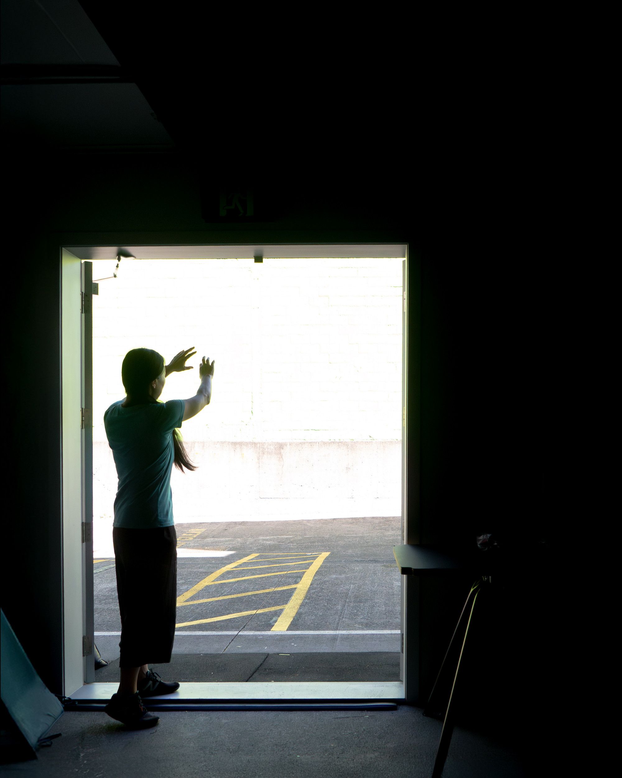 A person stands in a dark room with a door letting in sunlight