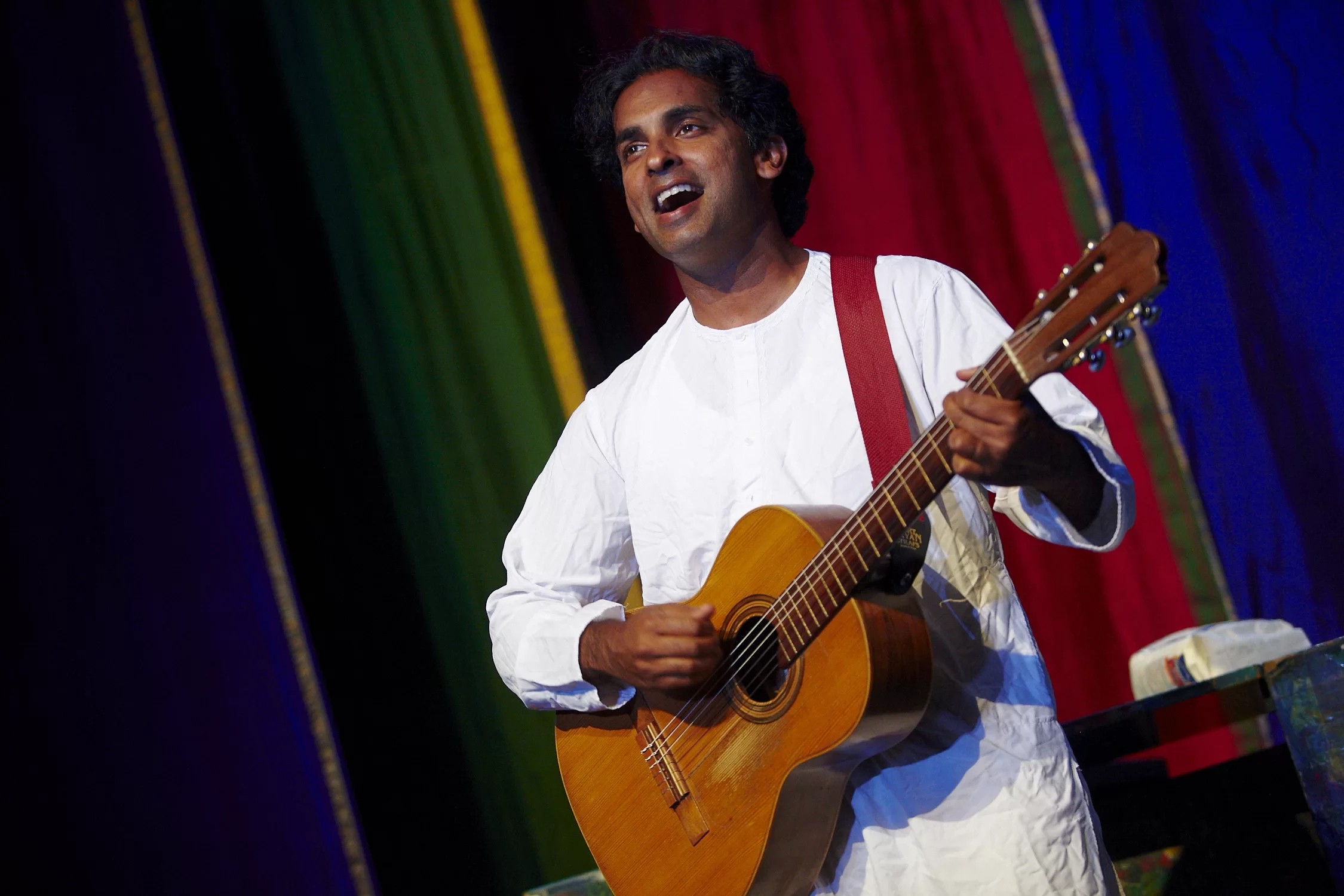 Jacob Rajan on stage singing and playing guitar.