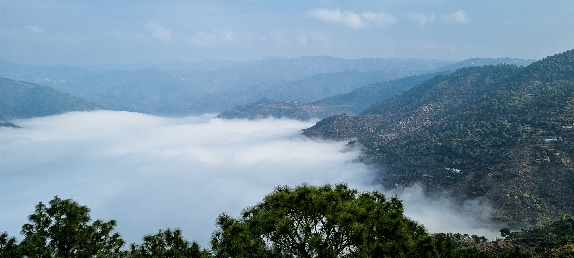 View from above the clouds of mountains stretching into the distance.