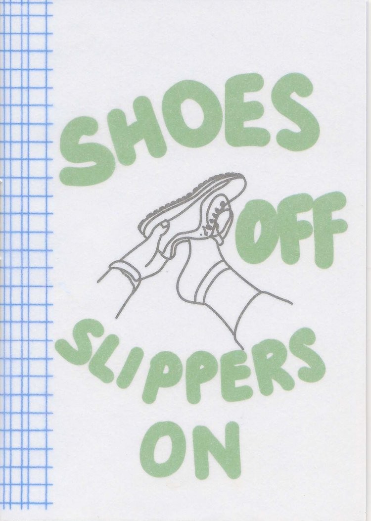 Shoes Off Slippers On in large green text with a black and white illustration of a hand taking off a shoe and blue simple tartan along the left margin.