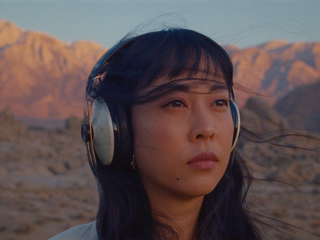 Close-up of a woman standing in the desert listening to headphones