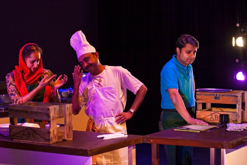 Three people behind a makeshift kitchen bench. In the middle is Amit Ohdedar in a chef's outfit