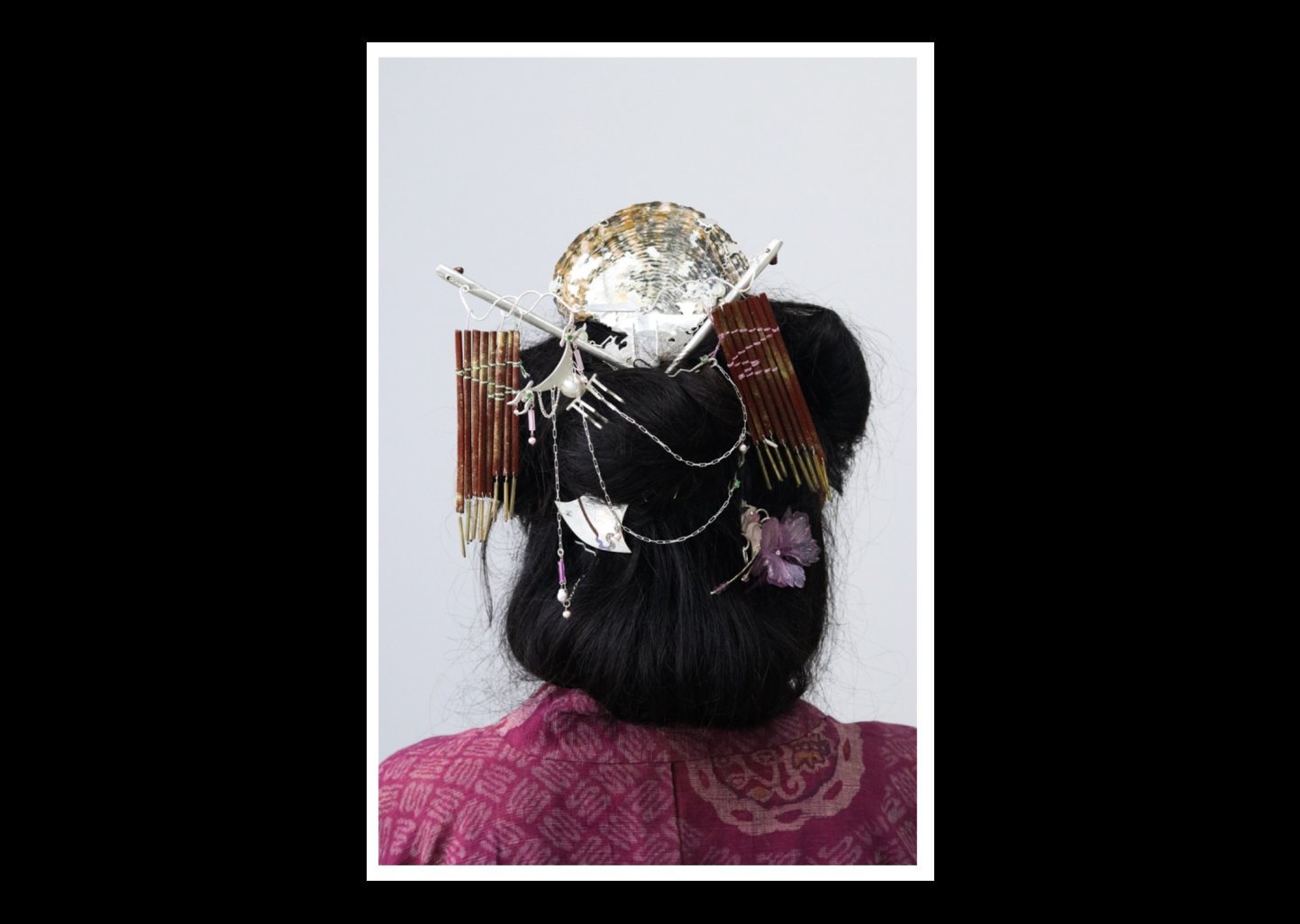 Photograph of the back of a head with many elaborate hairpins and ornaments.