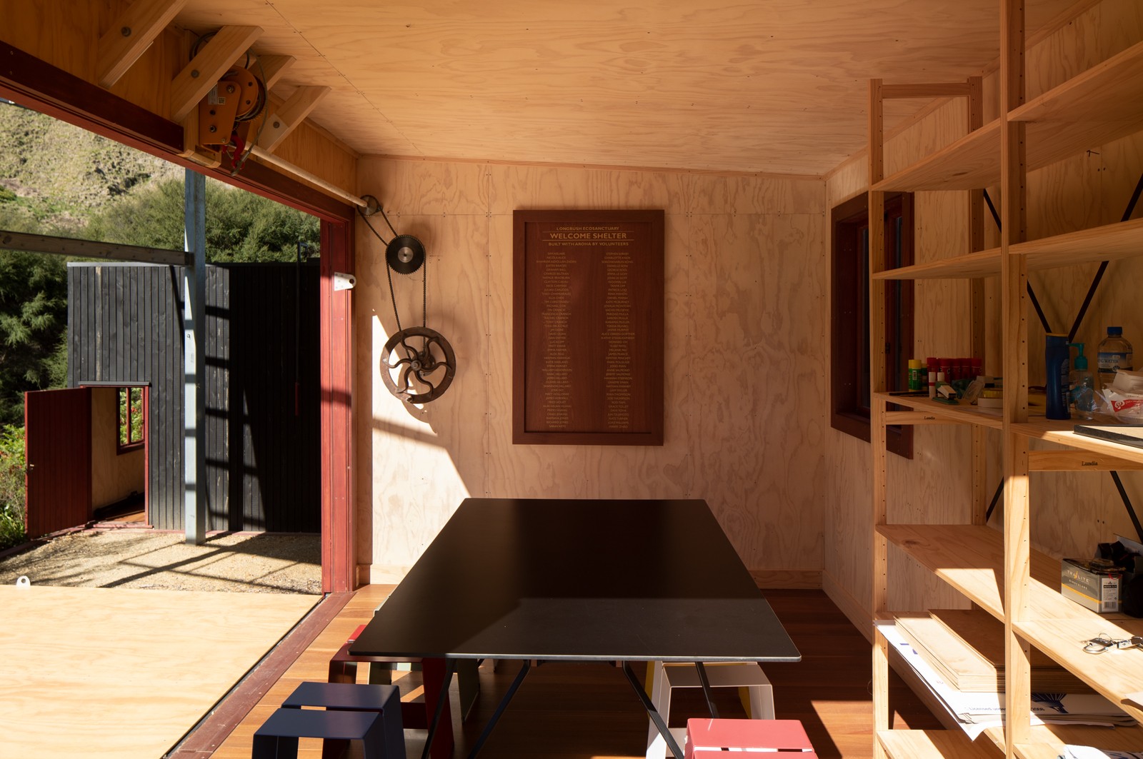 Interior view of a shelter made of plywood, with a classroom set up.