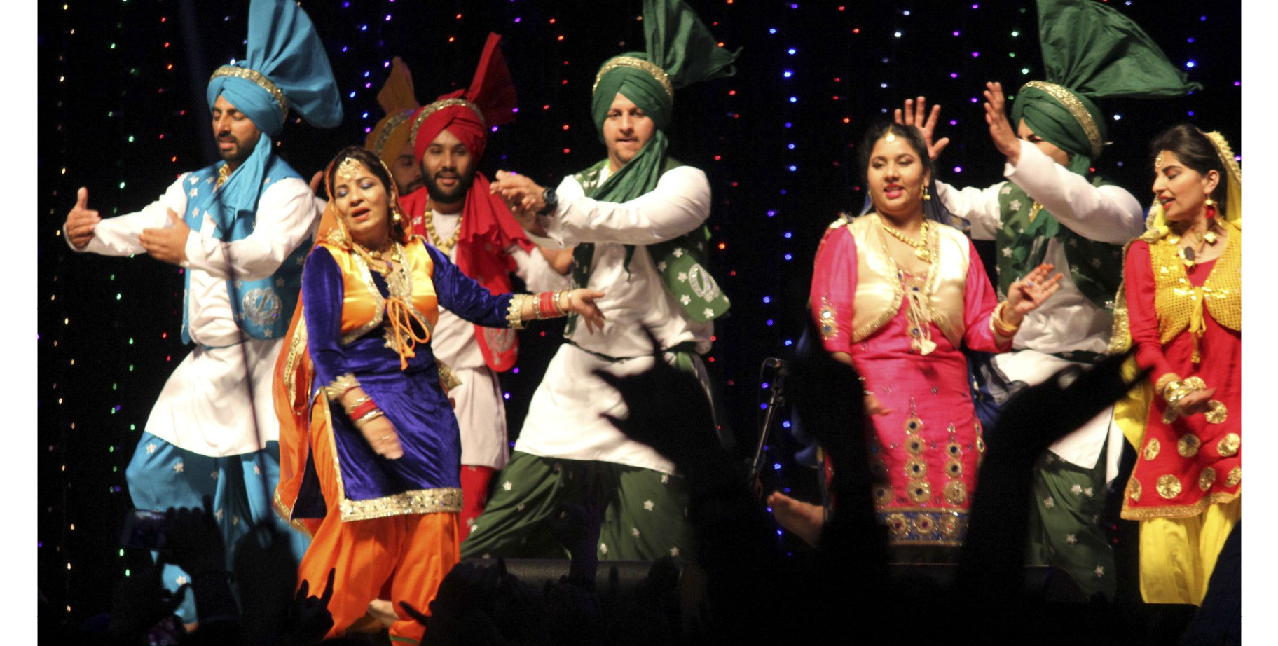 Indian dancers in colourful garments dance on a stage