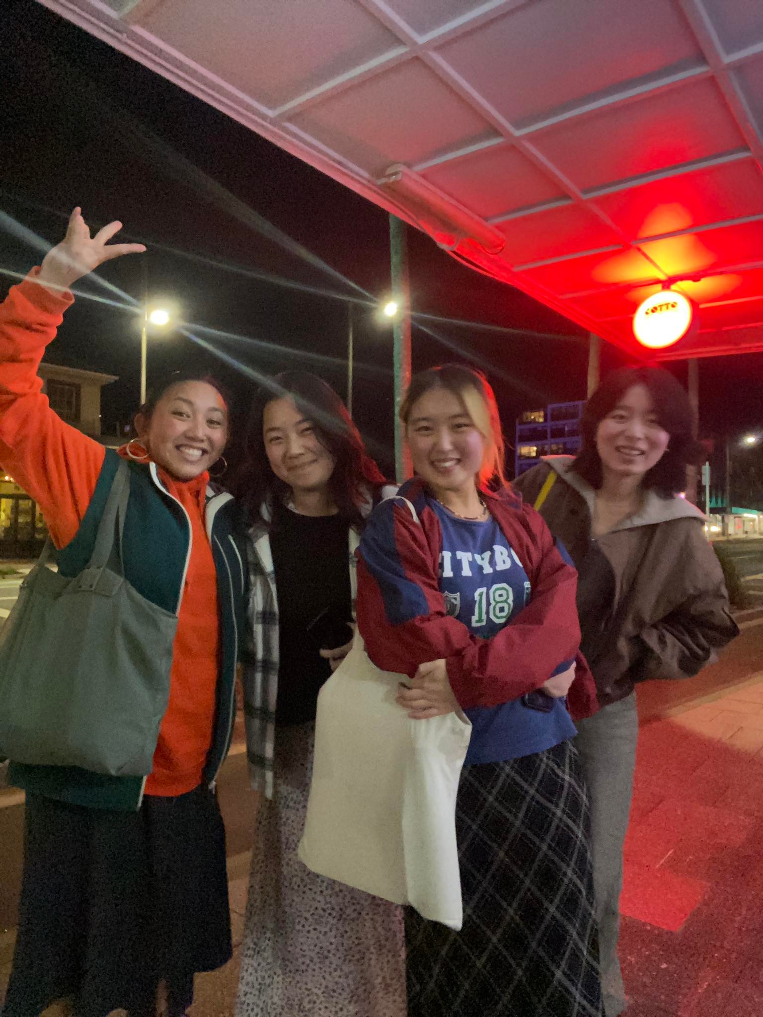 Four friends standing together on the footpath smiling at the camera