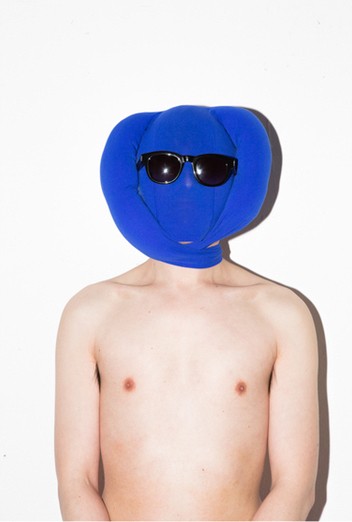 Man's naked torso and head completely adorned in blue fabric wearing sunglasses.