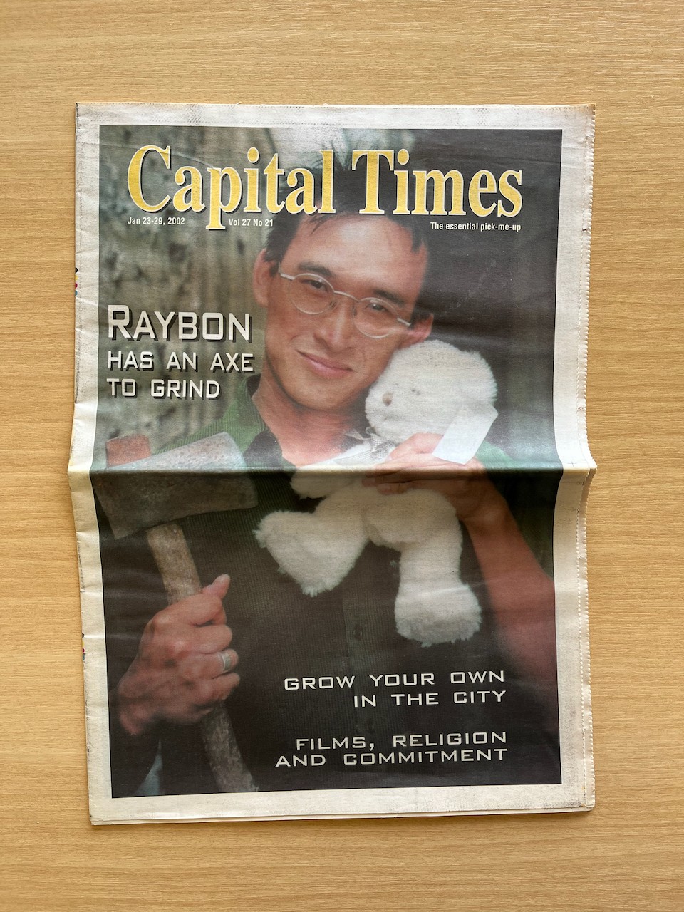 A young asian man holding an axe and a white teddy bear