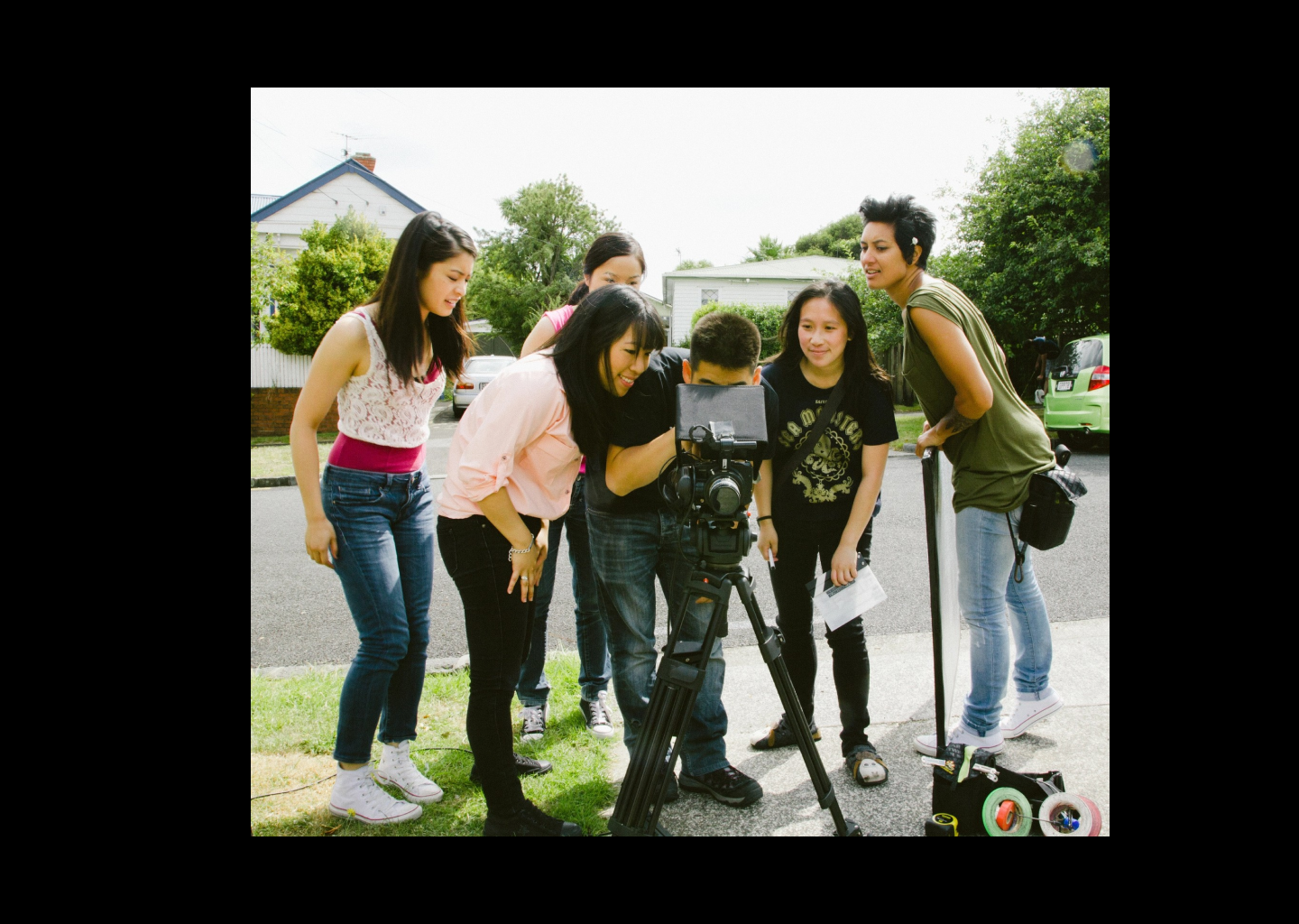 Cast and crew gather round a camera.