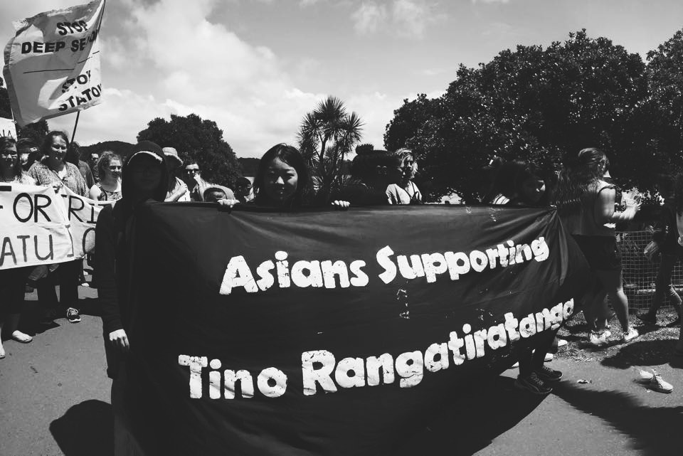 A group of people of Asian descent marching with a banner