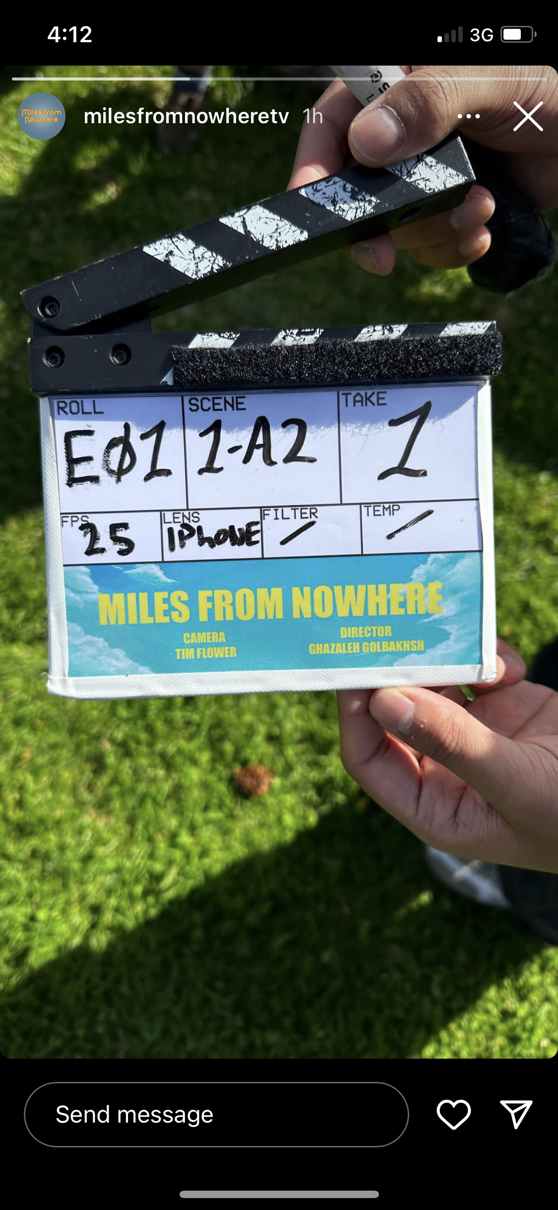 A close-up of a film clapperboard reading ‘Miles From Nowhere,’ held outdoors on a grassy lawn, with episode and scene details handwritten.