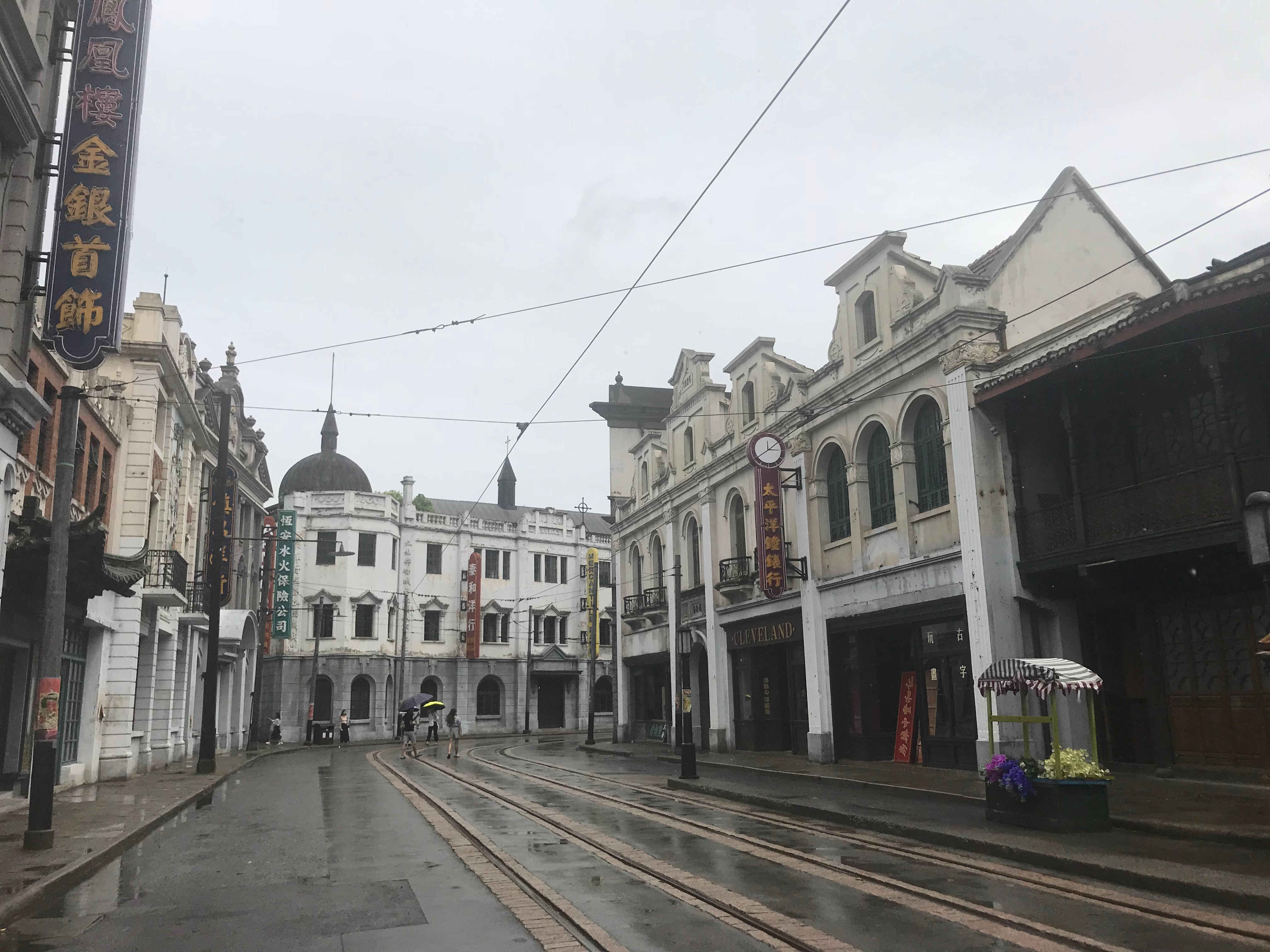 An empty street with three-storey white buildings and neon signage in Chinese characters