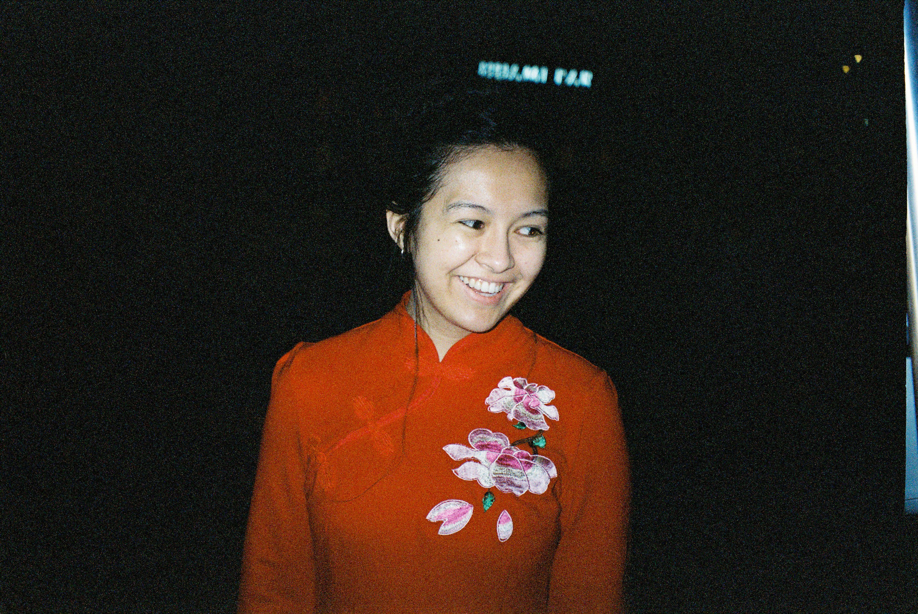 Jenn's hair is tied up and she is smiling and wearing a red cheongsam.