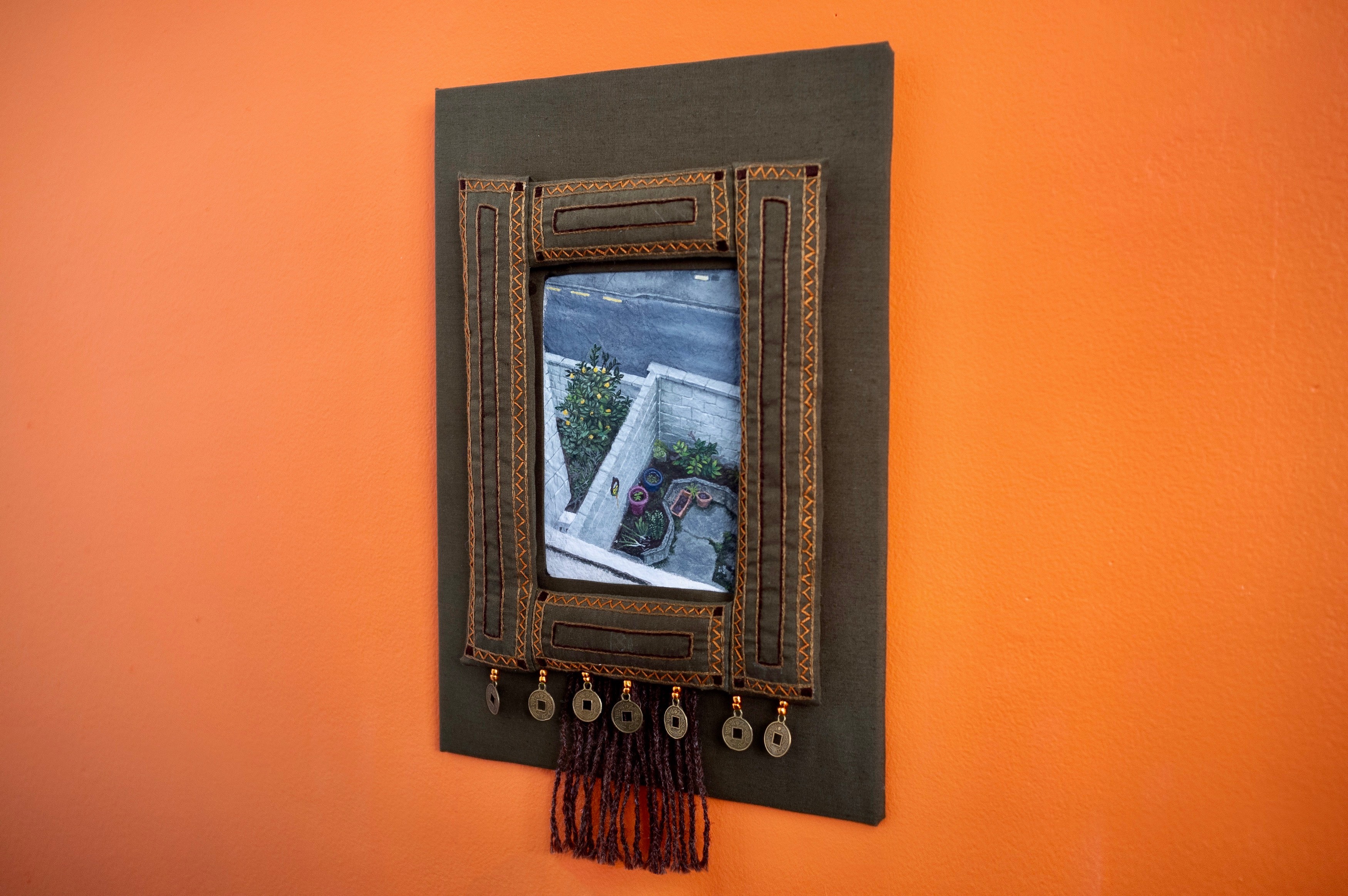 Photo of a embroidered artwork on an orange wall