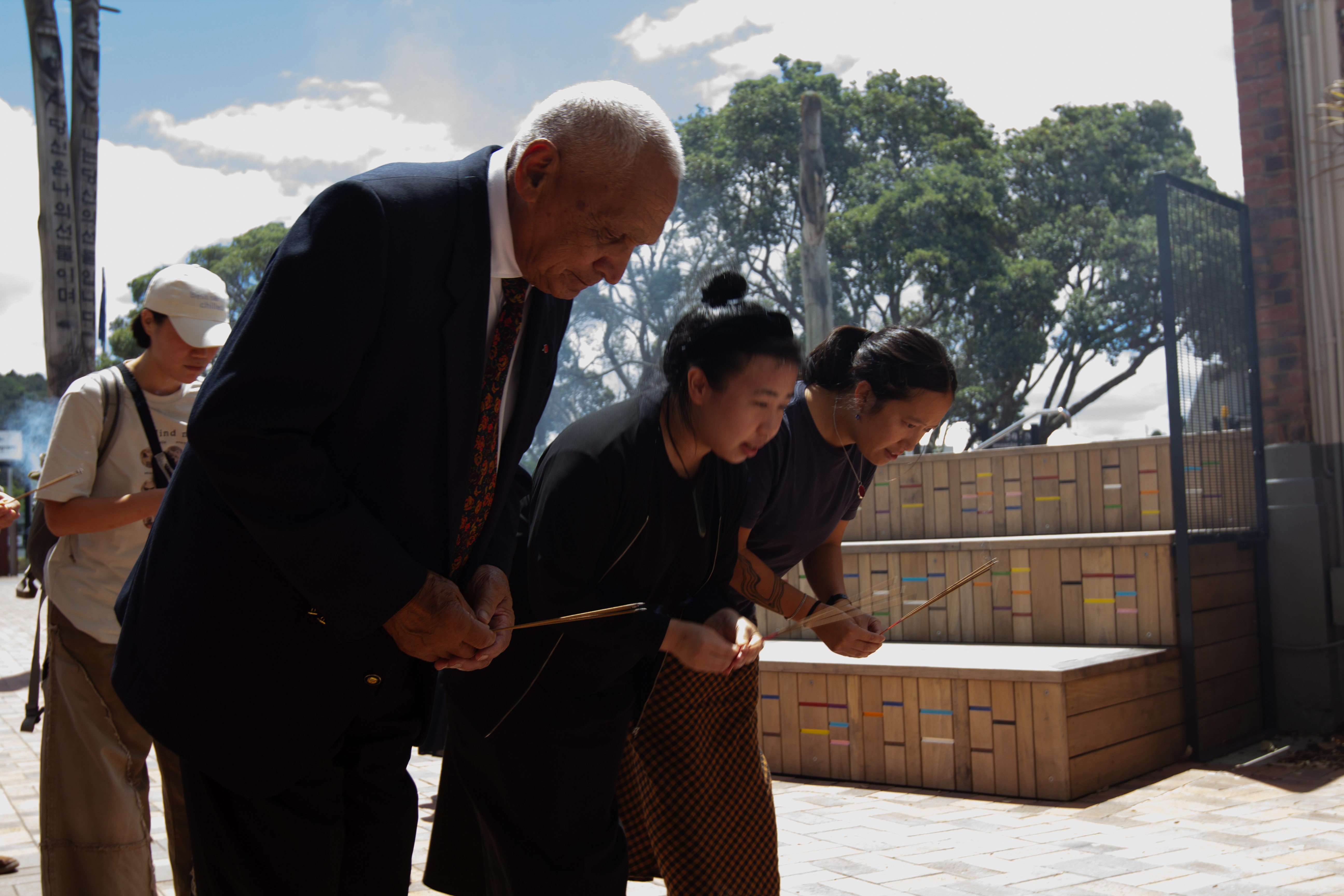 Three people bowing with incense