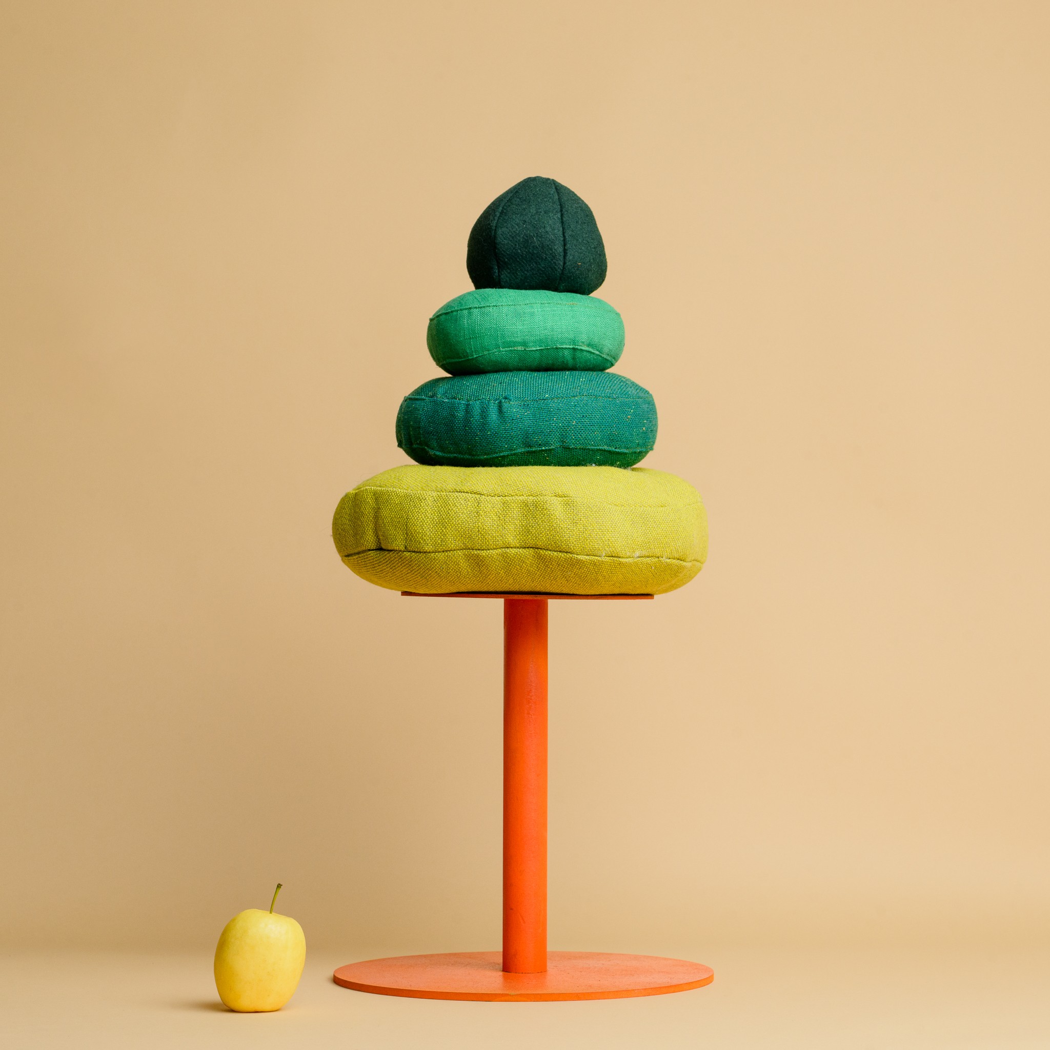 A tall tree made with three round green cushions on an orange plinth