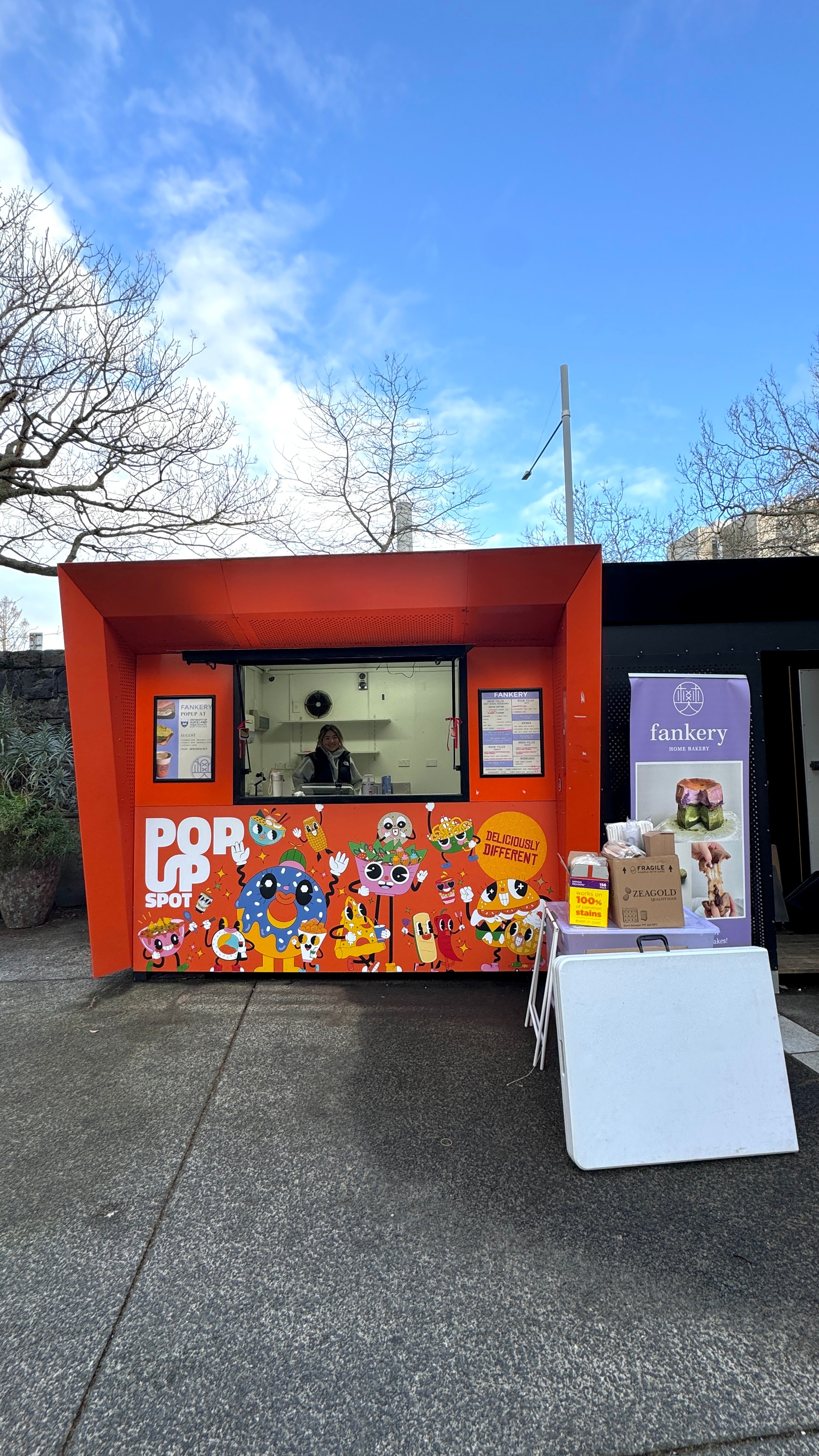 A reed food stall in a courtyard, decorated with many colourful characters.