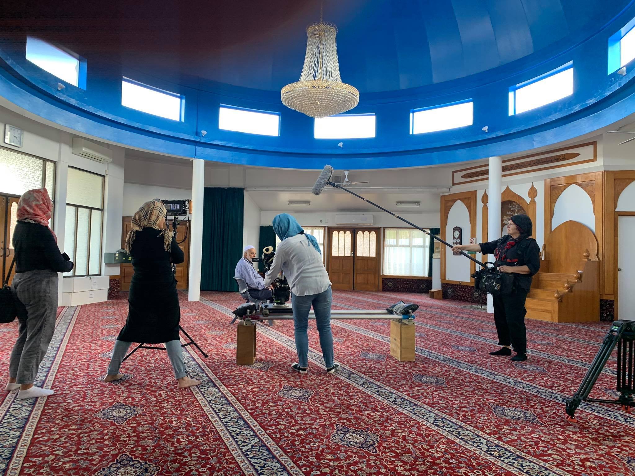 A behind the scenes photo of a documentary crew filming inside a mosque.