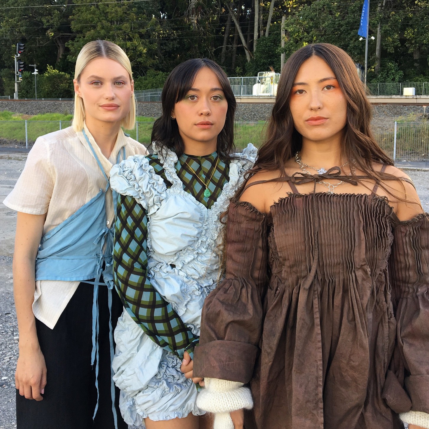 Three models wearing blue, brown and cream garments with lots of ruching and texture