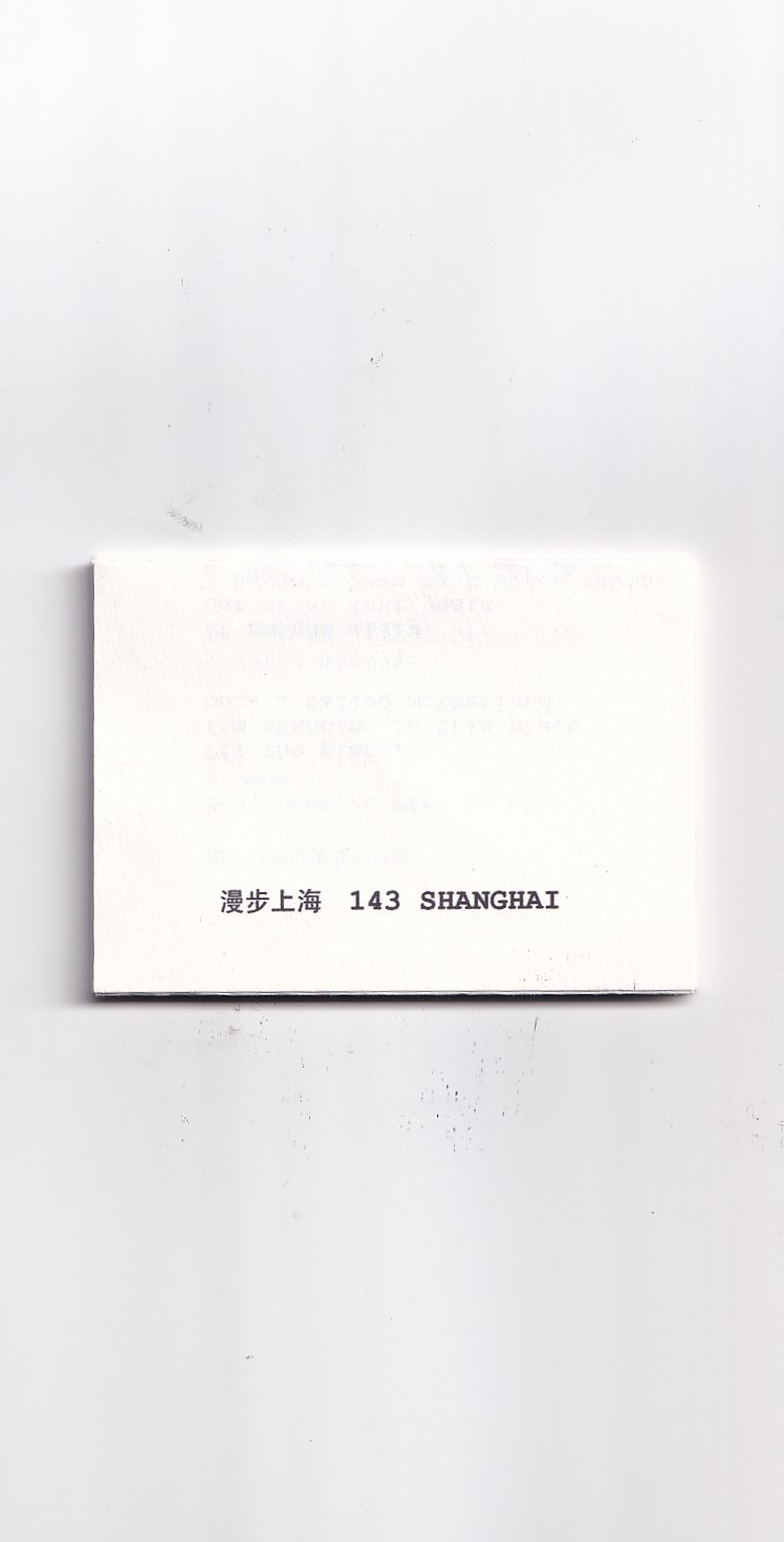 A white folded piece of paper with black text in both Chinese and English characters saying "143 Shanghai" 