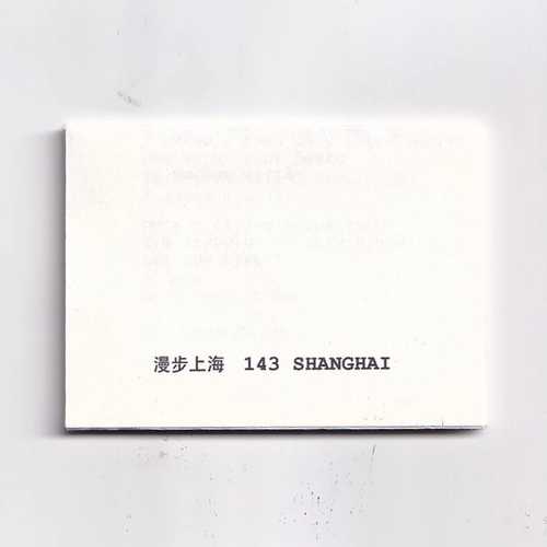 A white folded piece of paper with black text in both Chinese and English characters saying "143 Shanghai" 