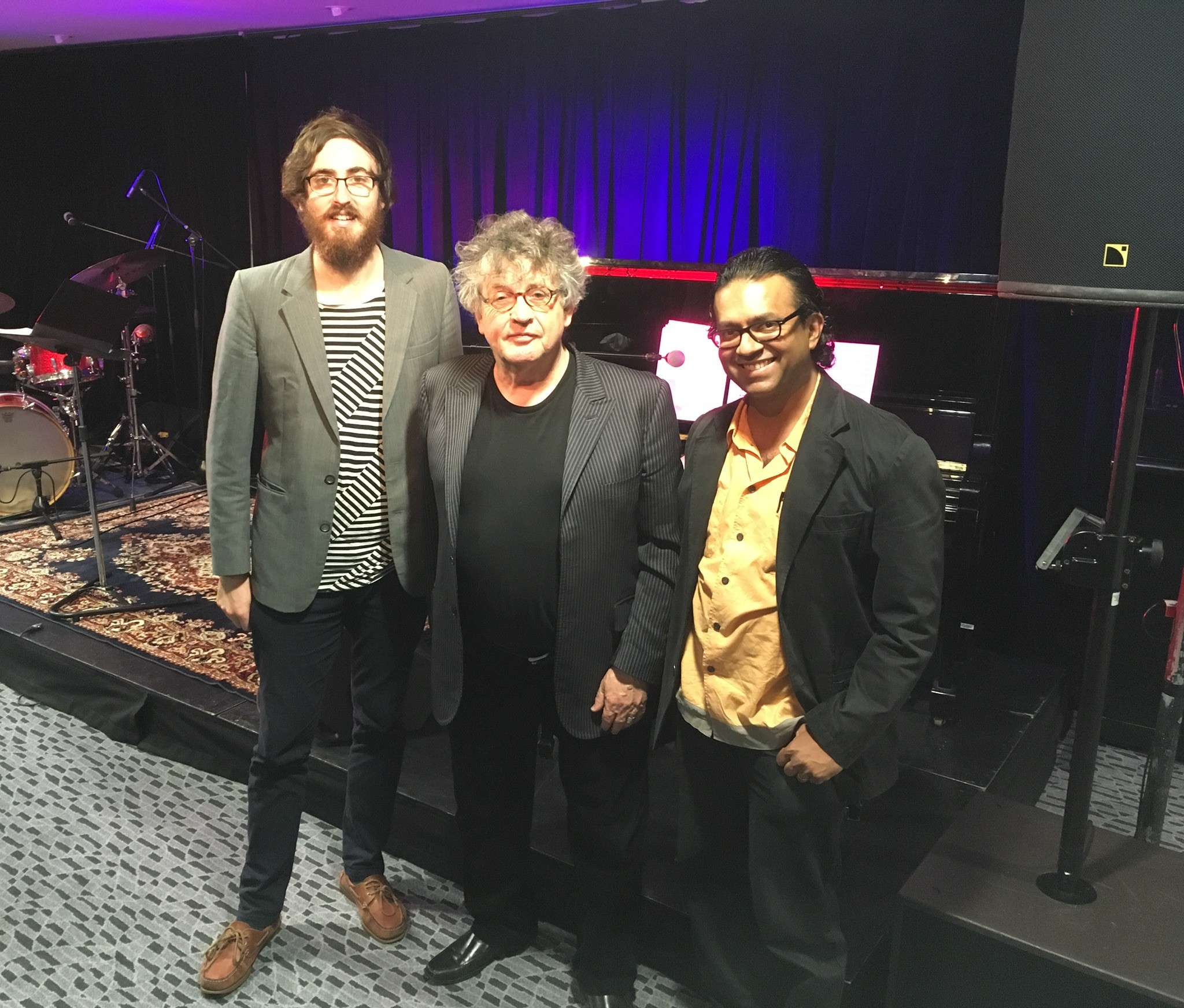 Three men standing in front of a piano