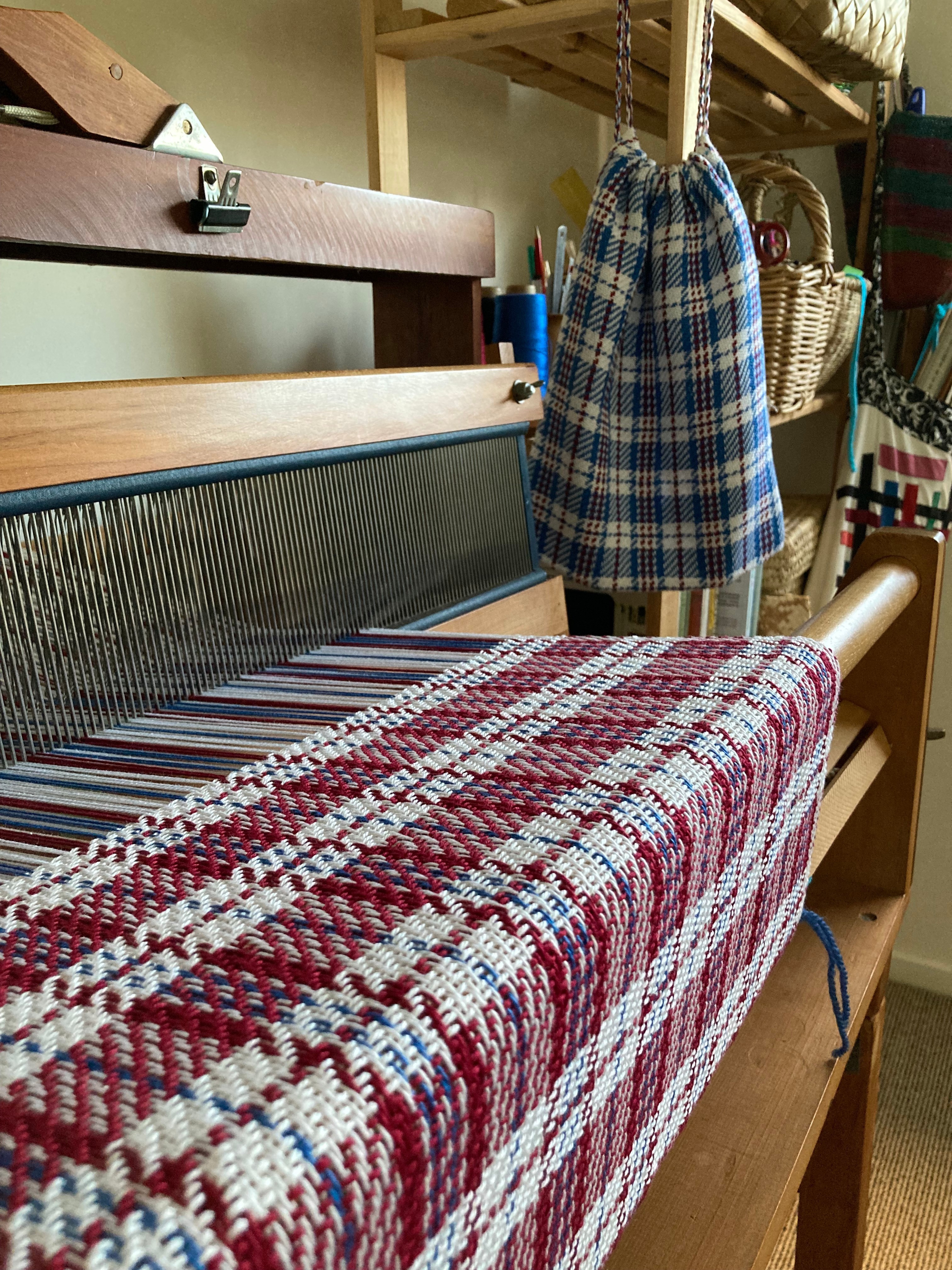 A weaving in-progress is shown still attached to the loom.