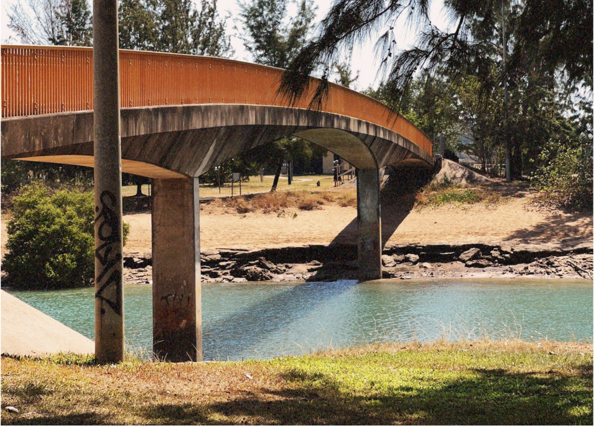 A rust-orange bridge curves across a river.