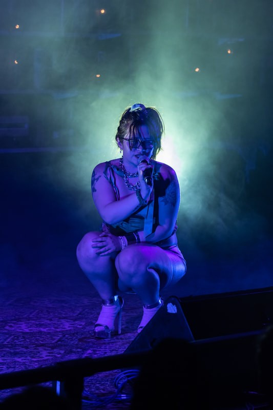 A performer holding a mic is bathed in purple light. 