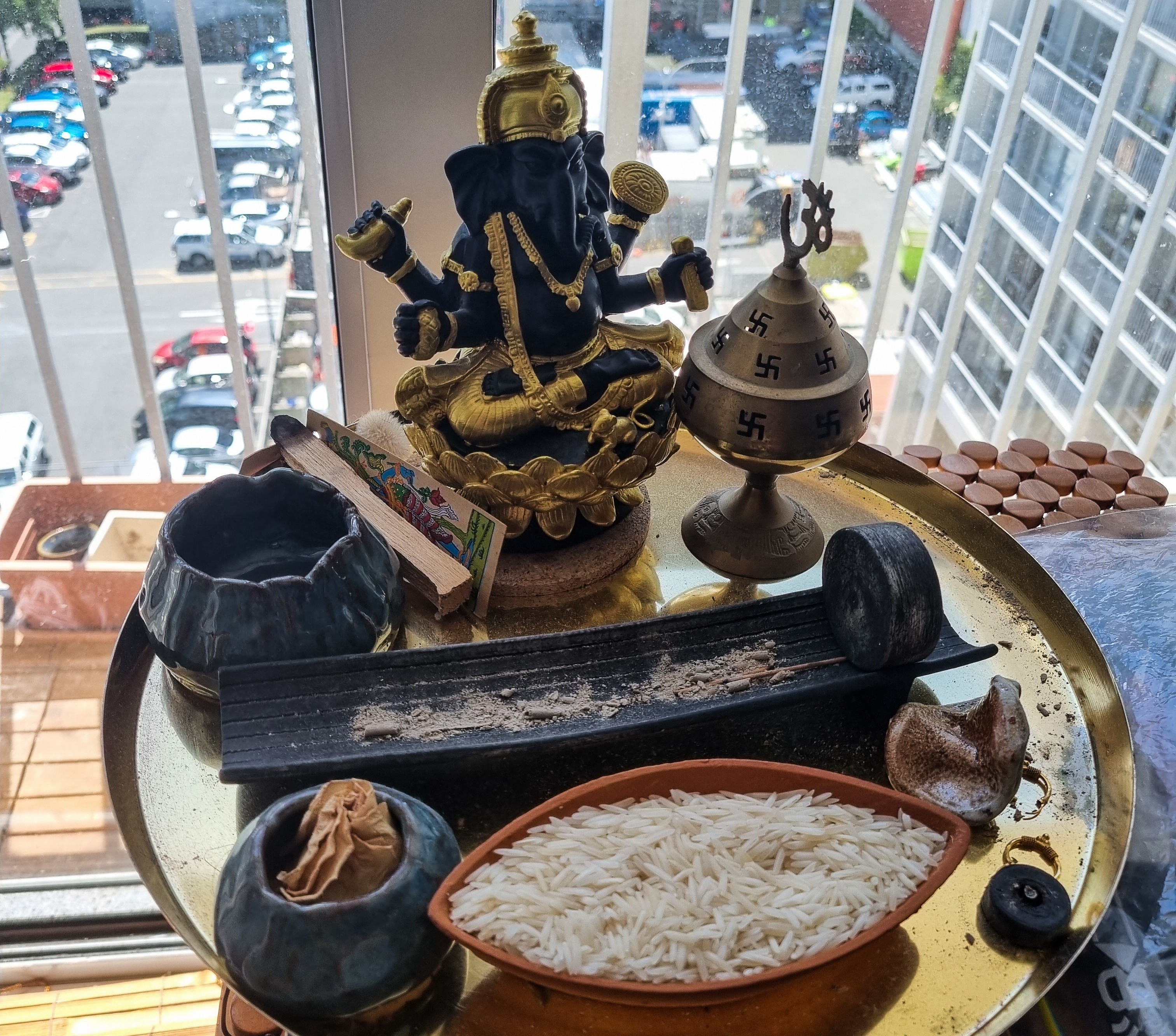 A collection of items on a tray: rice, incense and a statue of Ganesh.