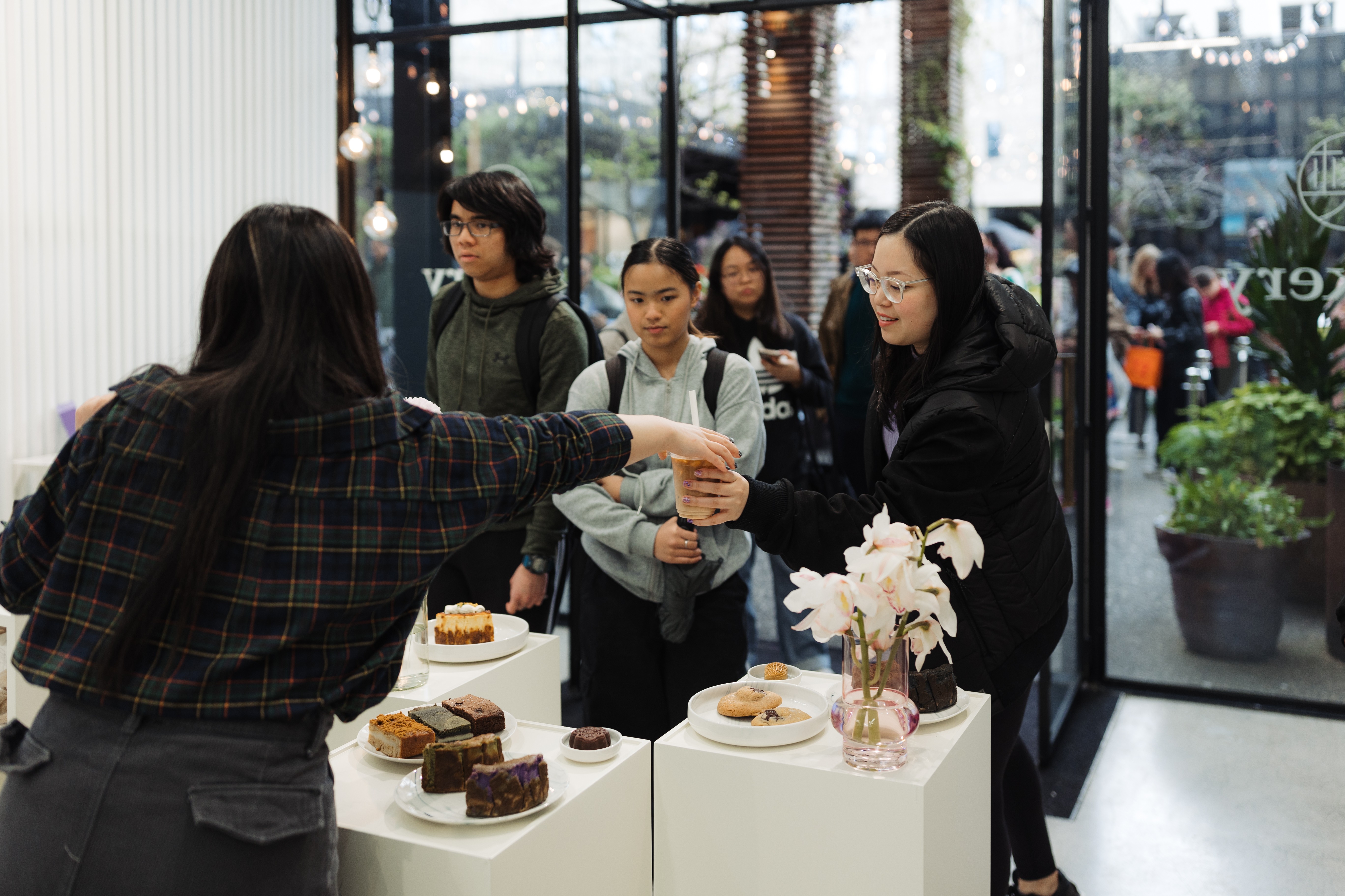 Customers purchase baked goods which are sitting on plinths.