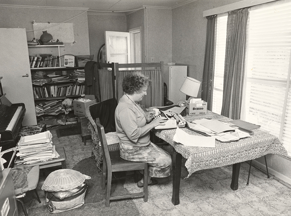 Black and white photograph of Janet Frame writing at a table on a typewriter.