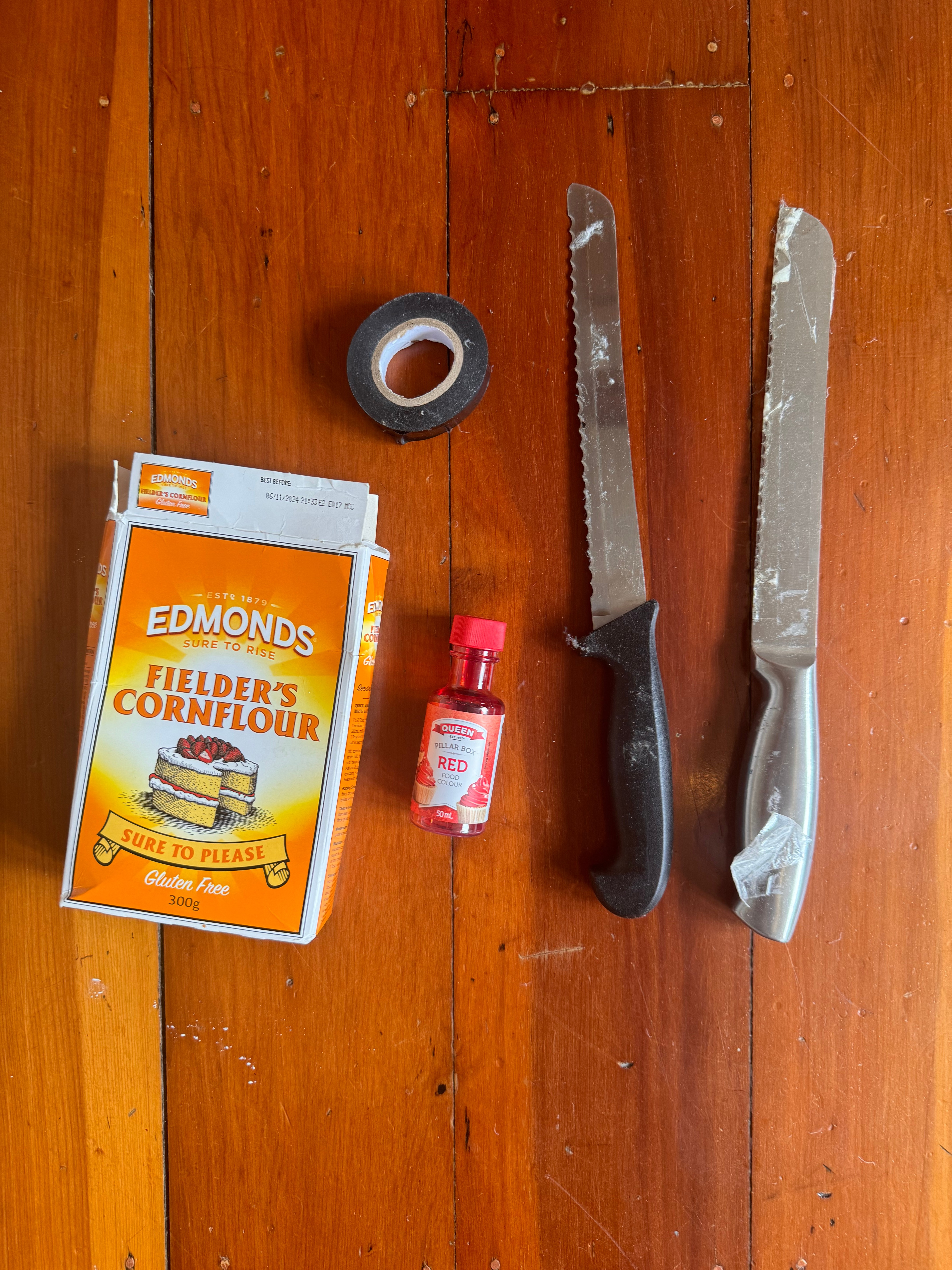 A box of Edmonds cornflour, a roll of tape, food colouring and two knives.