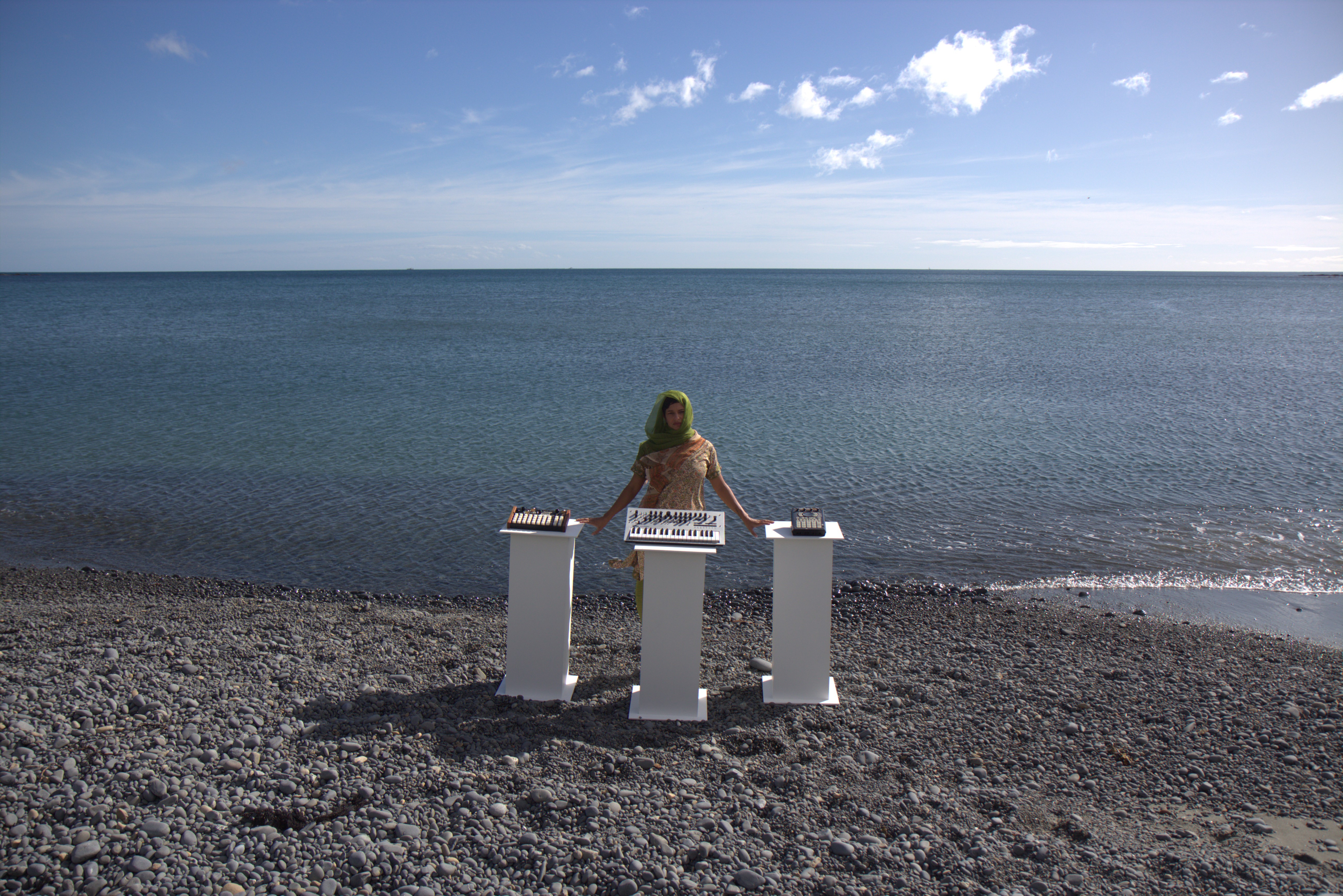 A person standing in front of three plinths on a beach