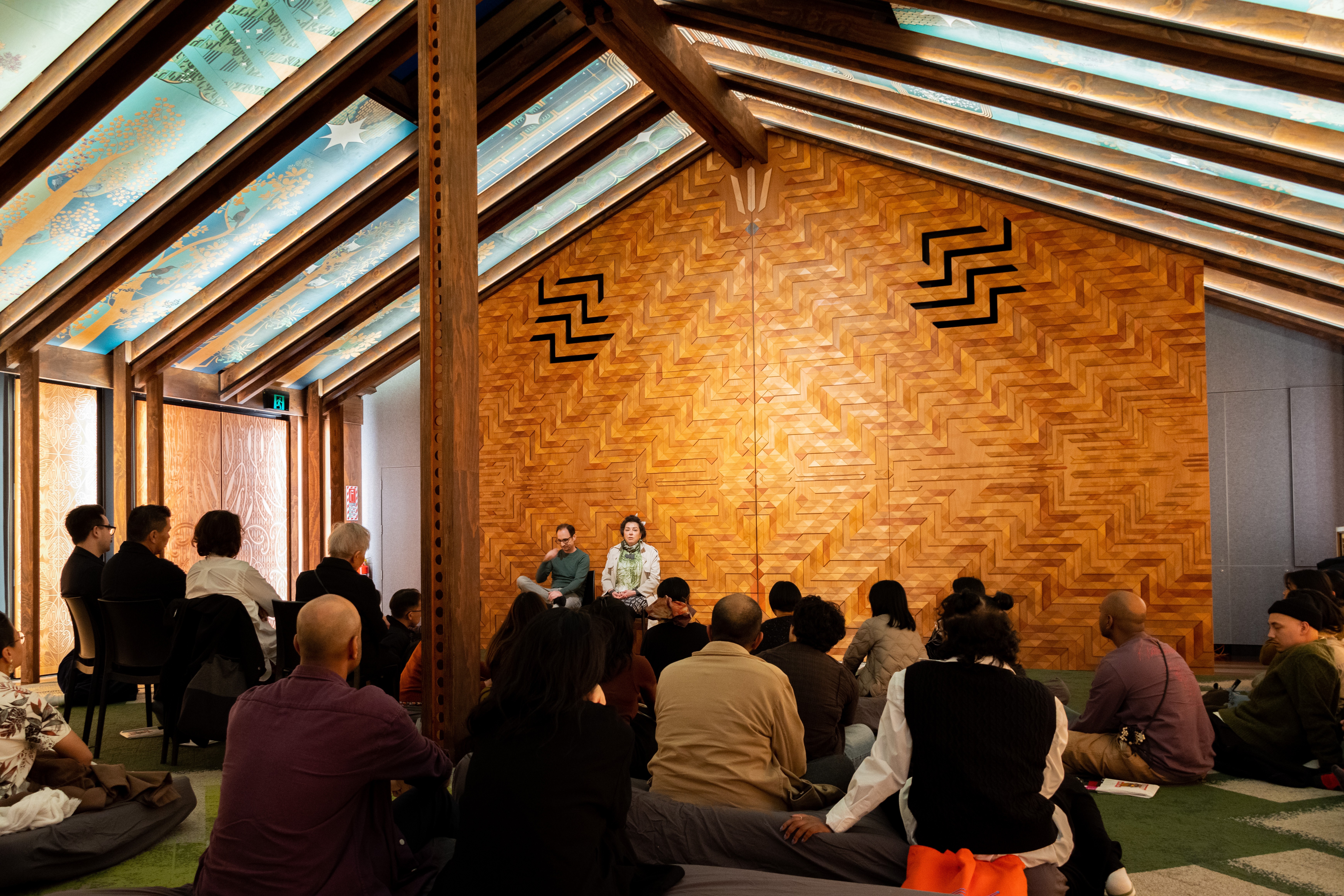 A man in glasses and a woman with a coat on address the group