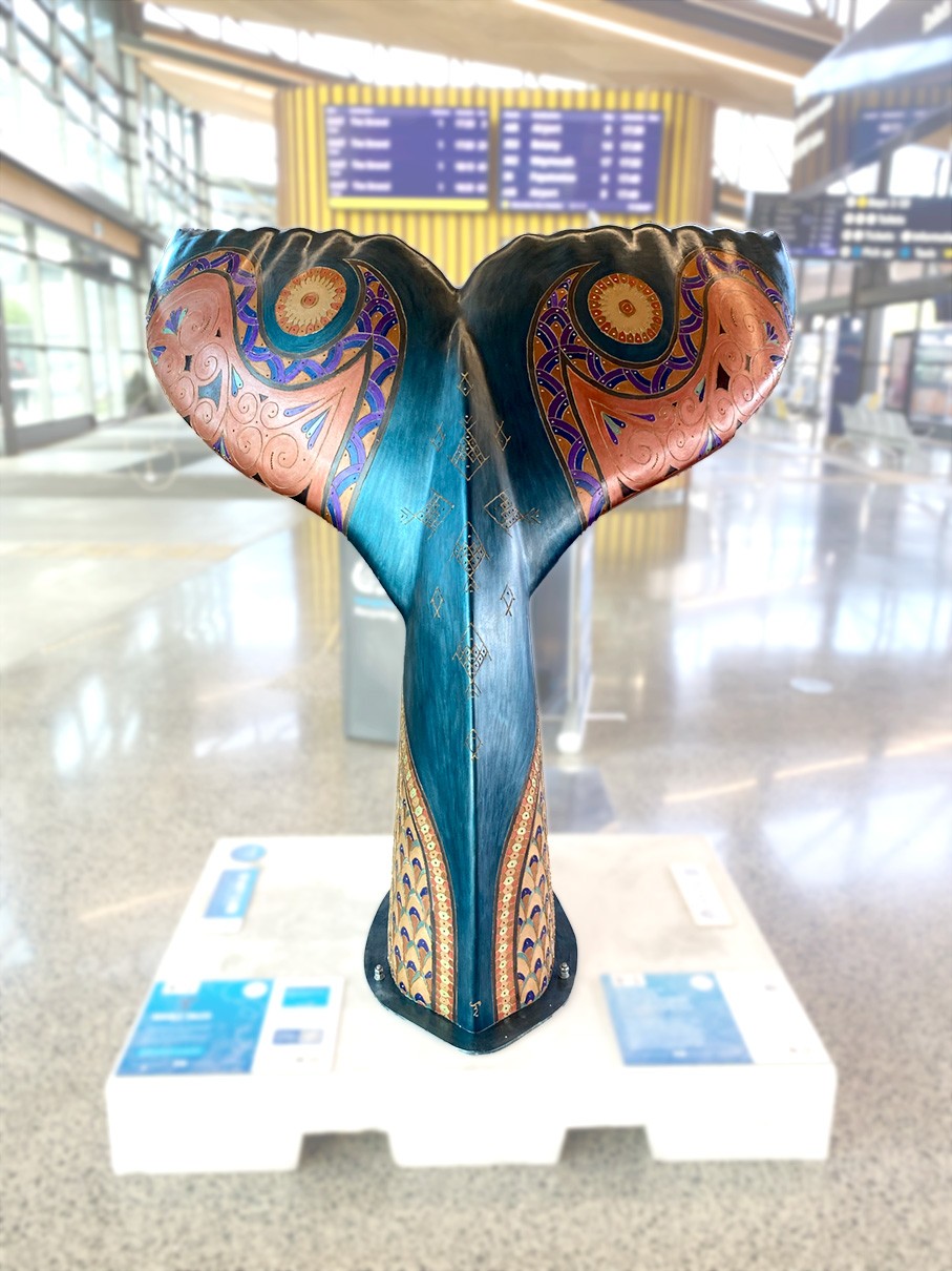 A sculpture of a blue whale tail with colourful patterns and symbols p