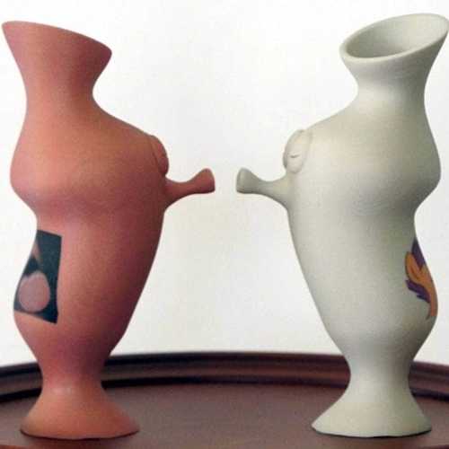 Two anthropomorphic vases lean towards each other, eyes closed and lips puckered for a kiss.