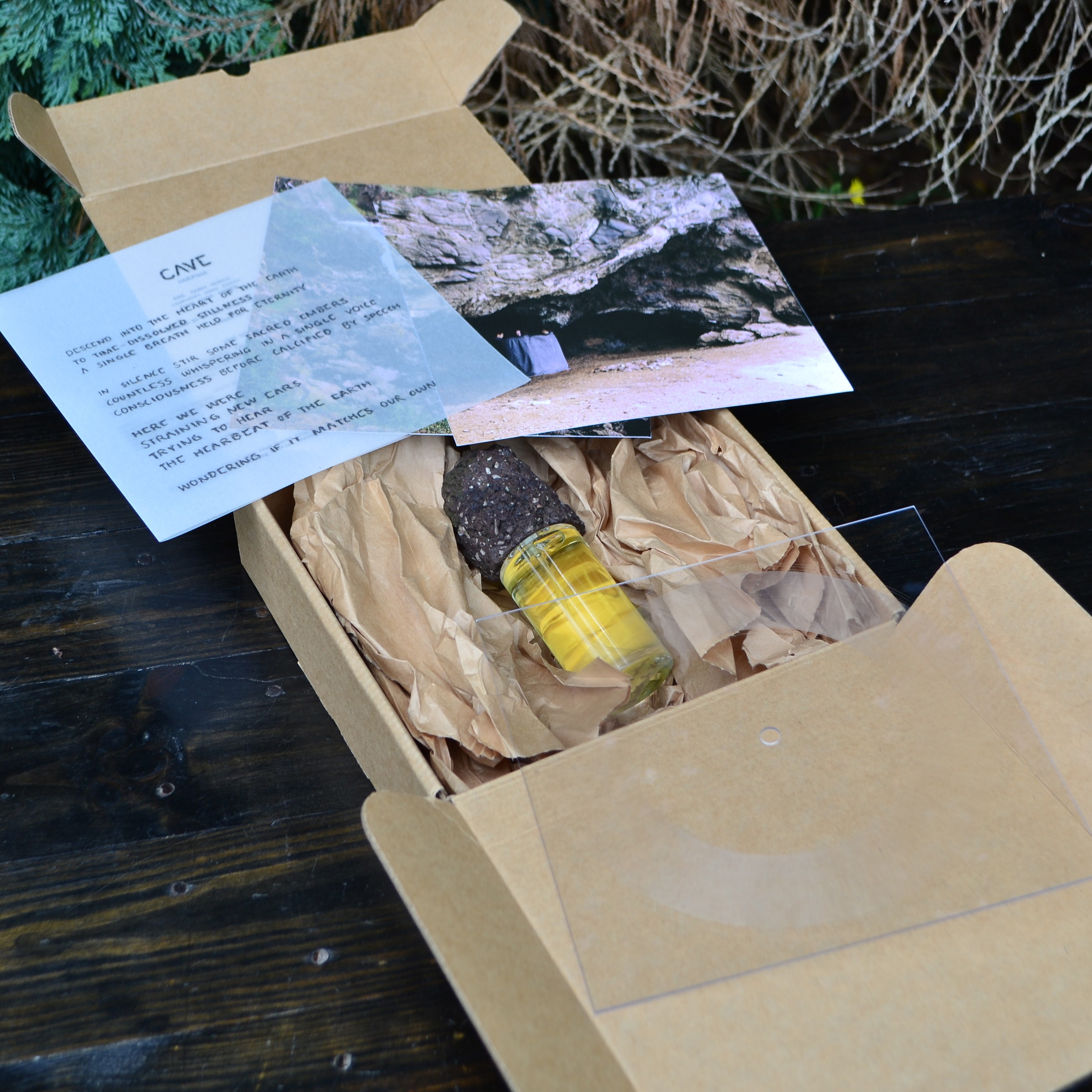 An open cardboard box with a perfume, photograph, note and lathe-cut record.