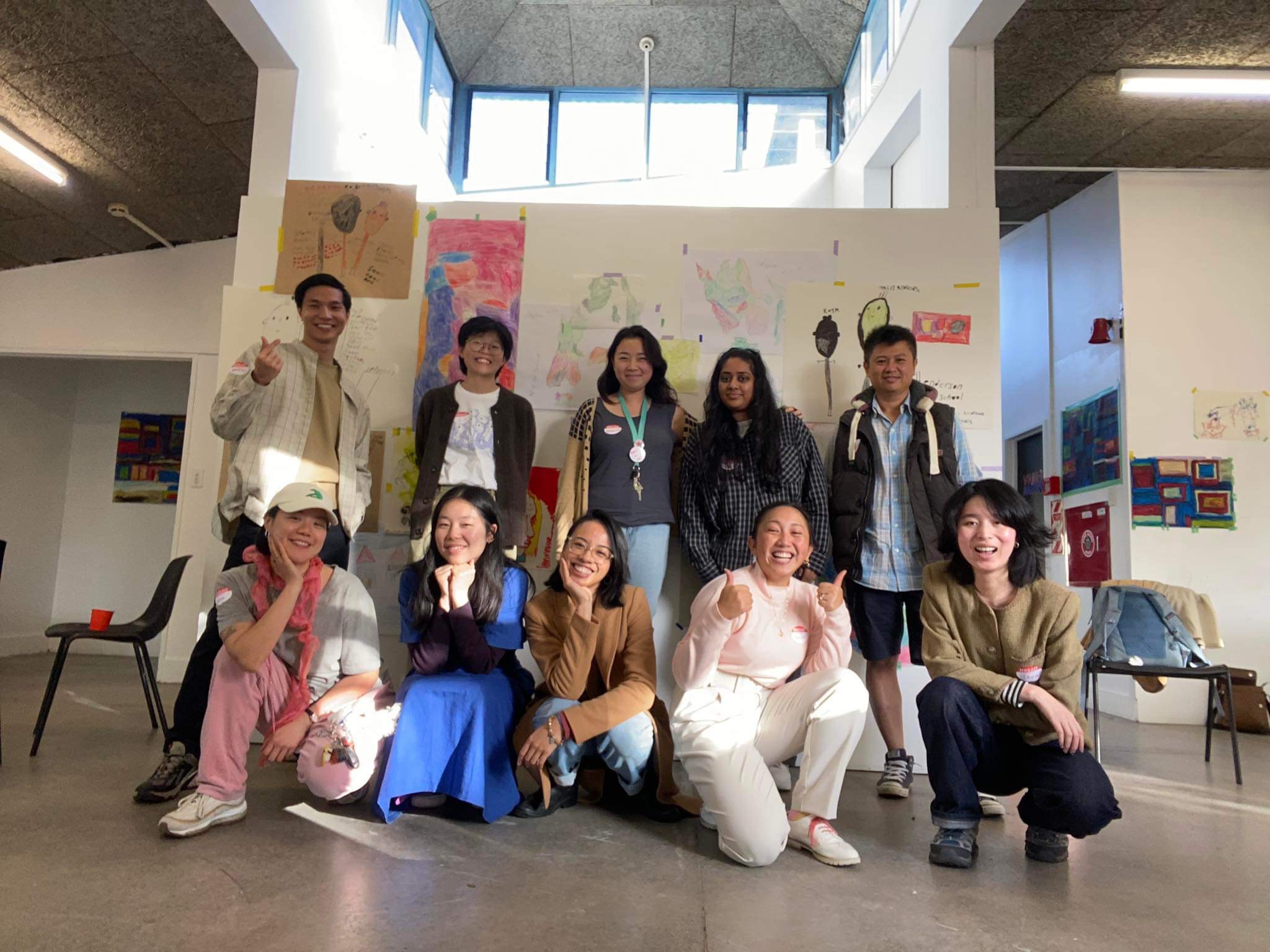 A group of artists pose for a photo together in an art gallery.