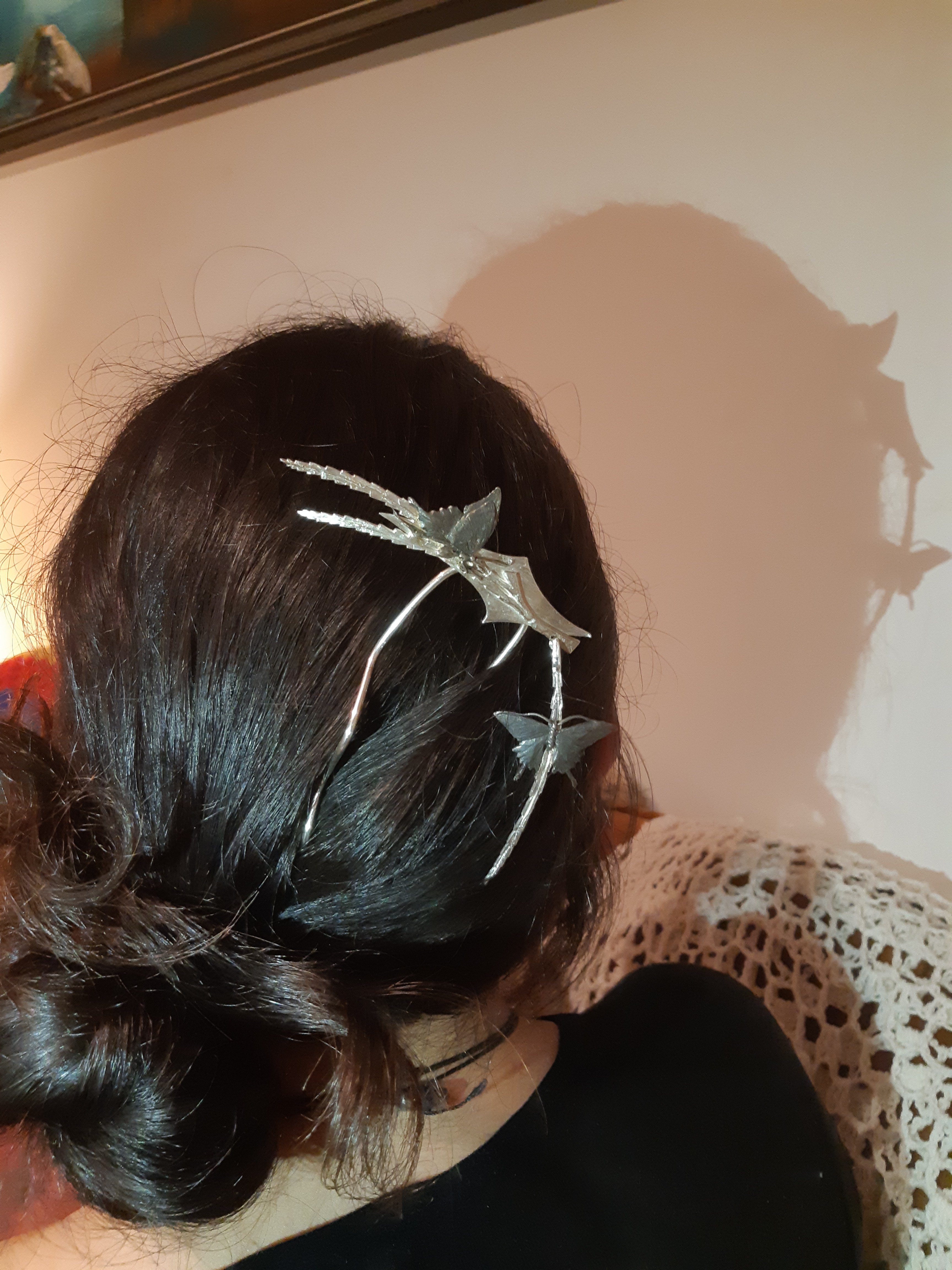 A woman with long brown hair held up by a kanzashi, faces away from the camera