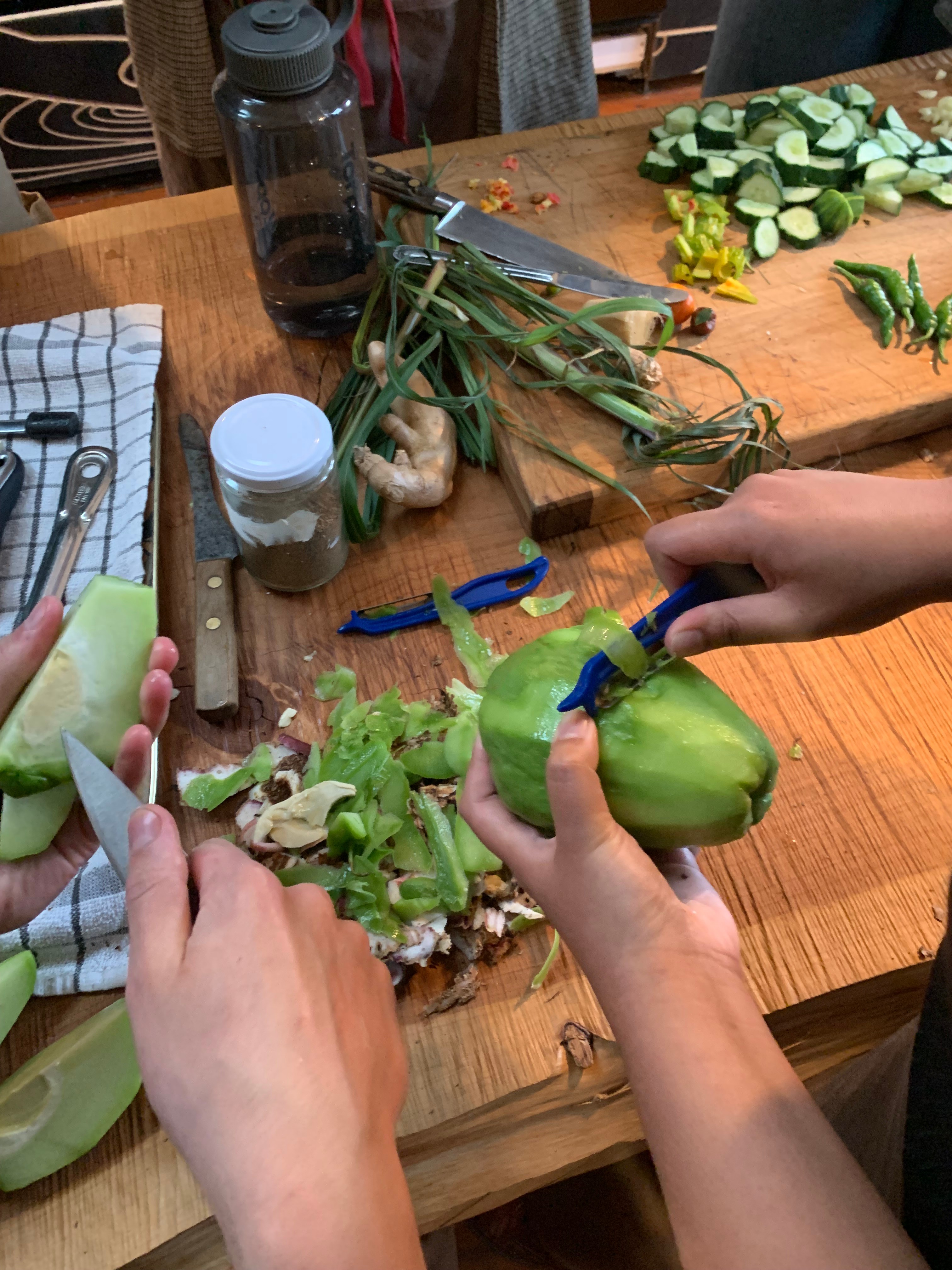 Hands peeling a choko.