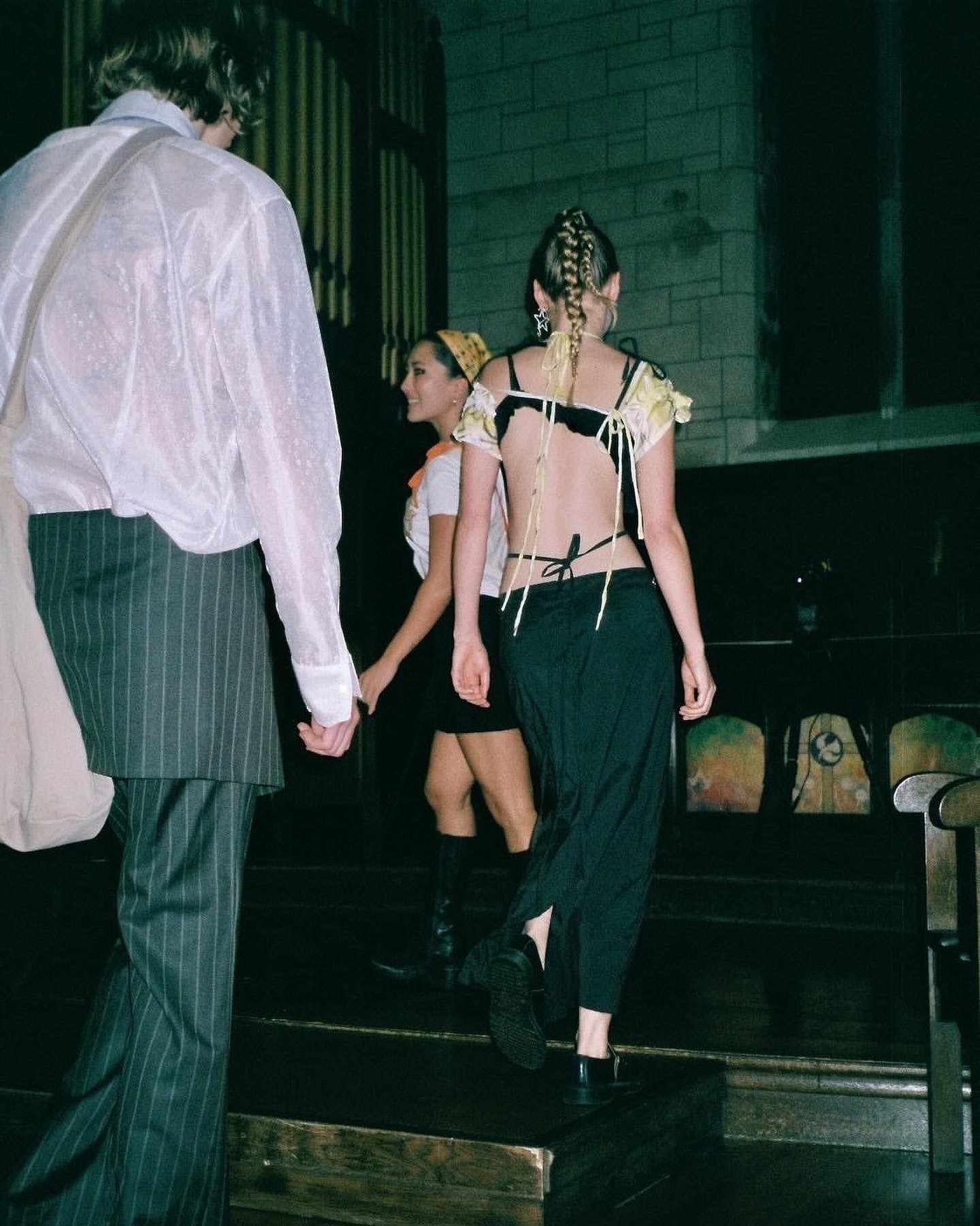 A model in a black and white outfit with a cutout back walks away from the camera at a fashion show