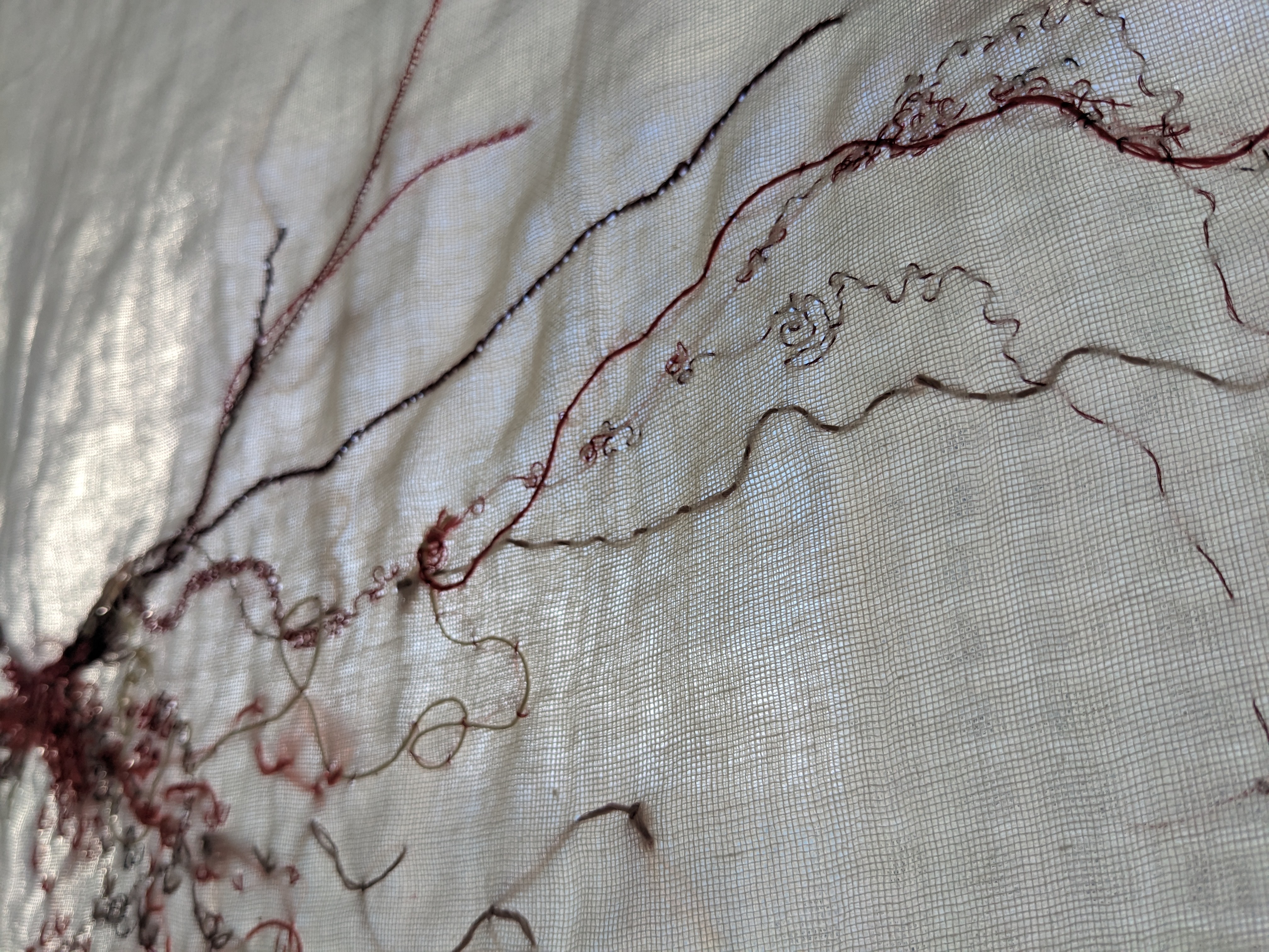 A sheer white piece of fabric with red lines embroidered onto it