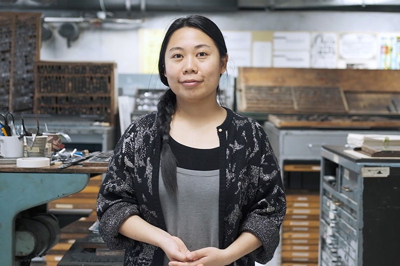 A person smiling in front of letterpress materials