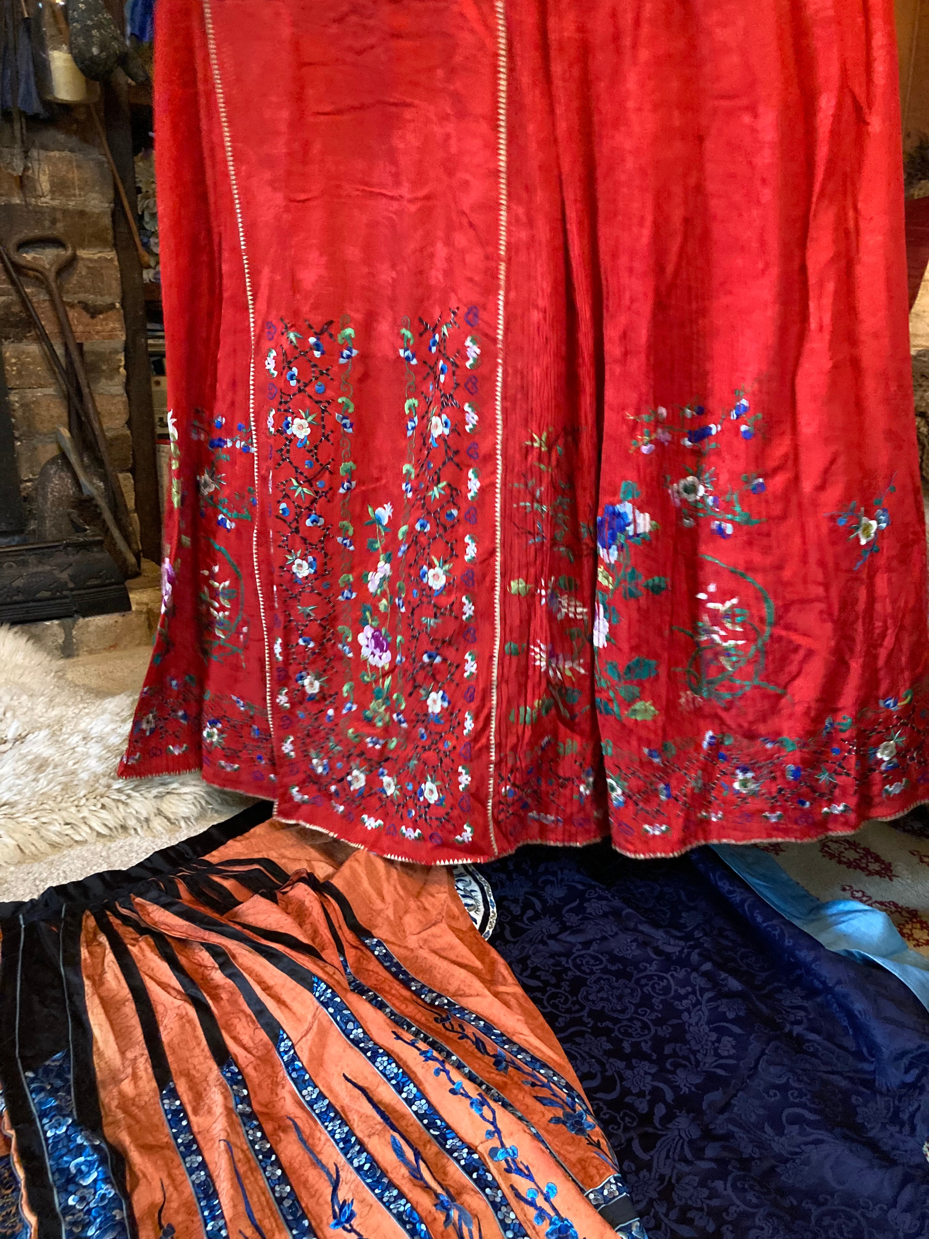 Two embroidered silk skirts, one orange and blue, the other a vibrant red.