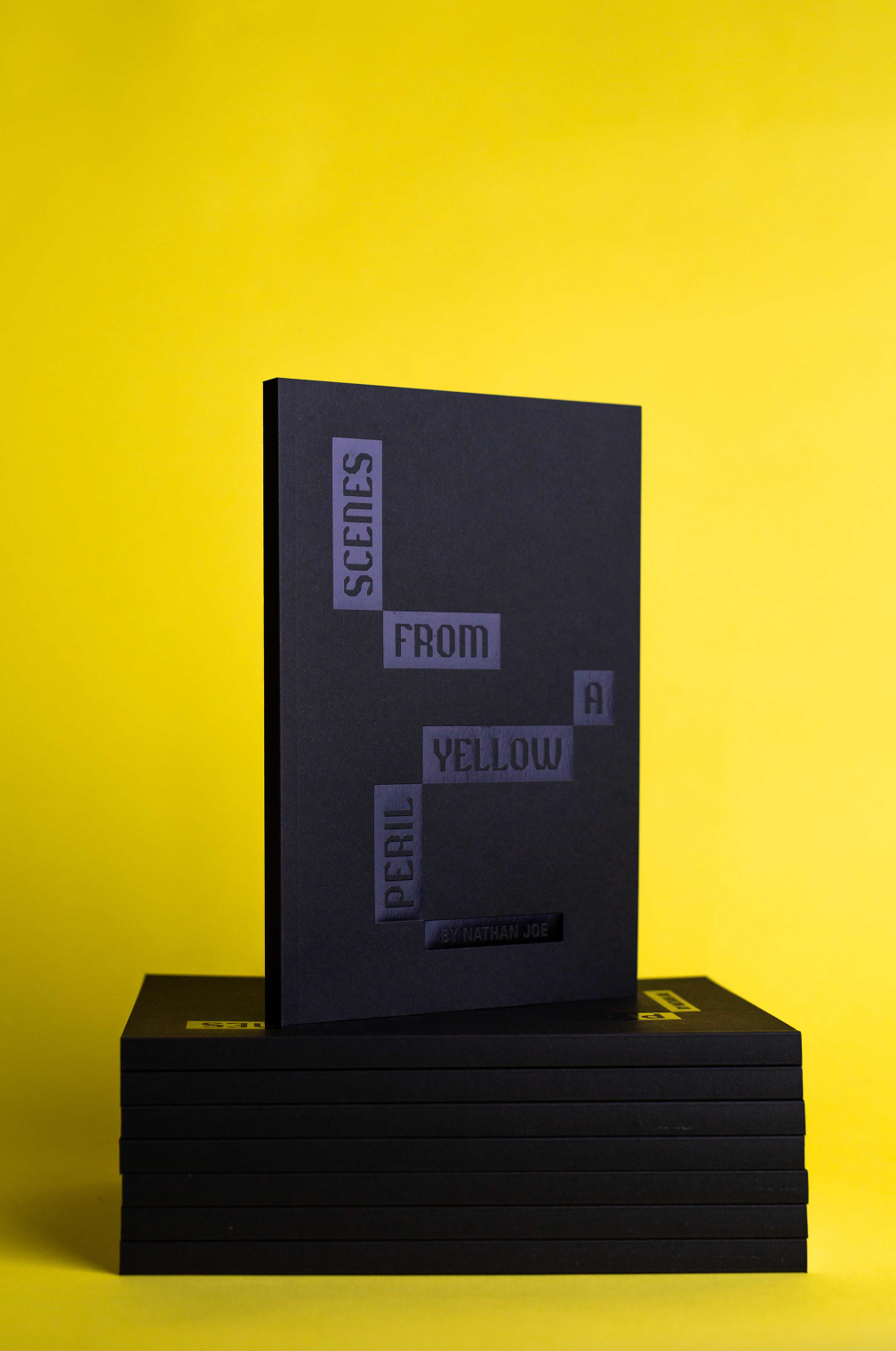 A stack of black books on a bright yellow background.