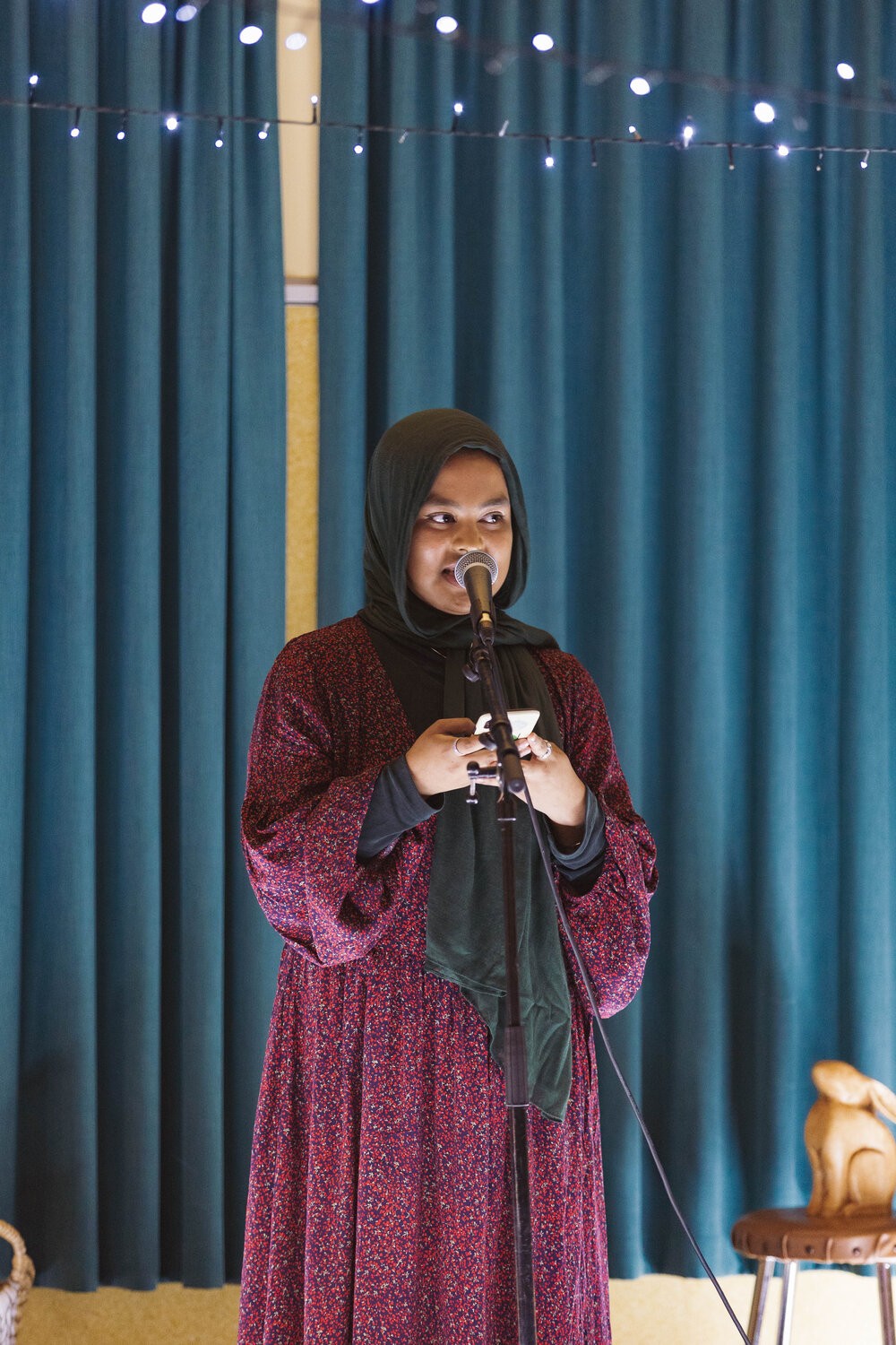 A person holding their phone and speaking into a microphone.