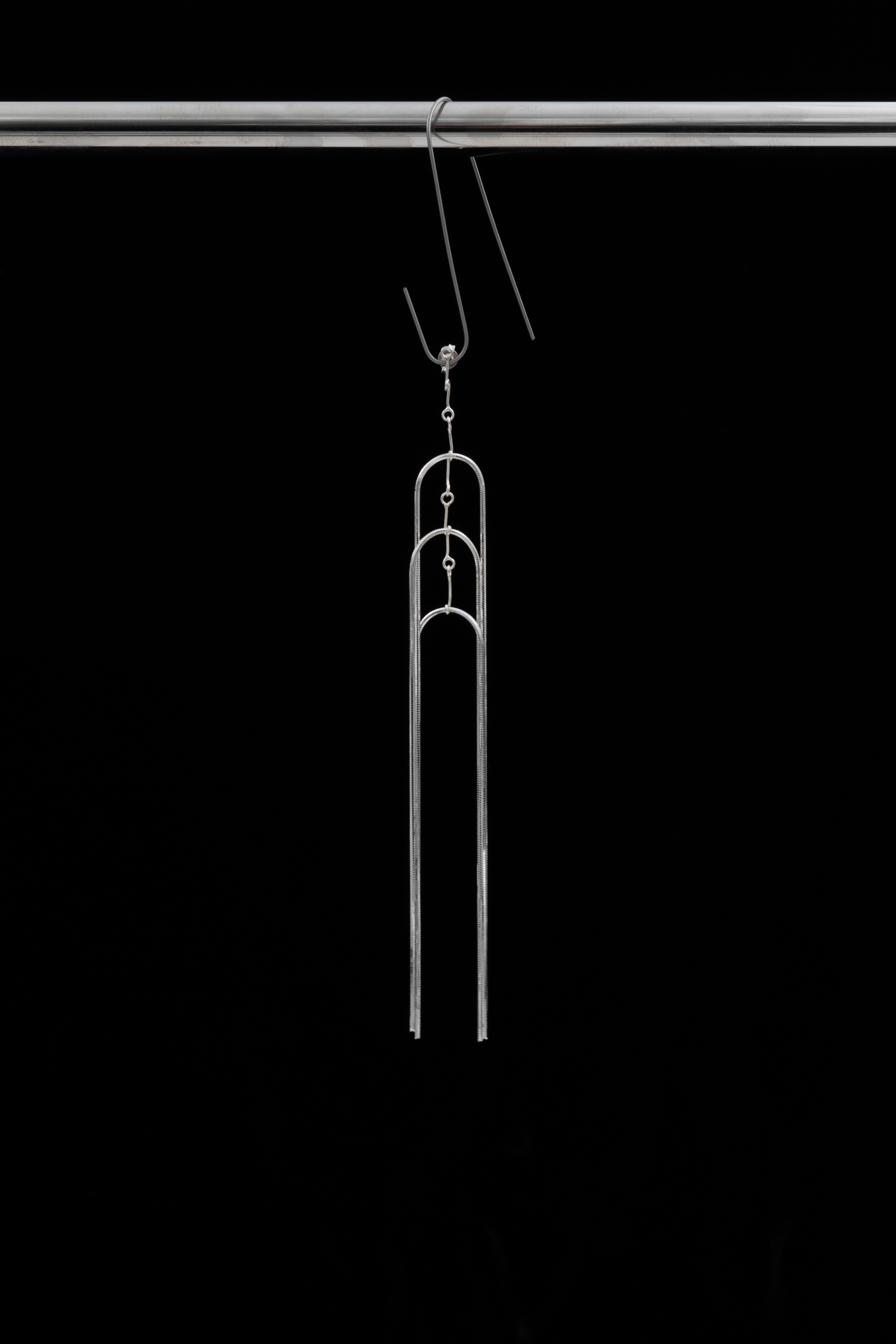 A delicate single earring, with two upturned u-shapes held together by a central chain