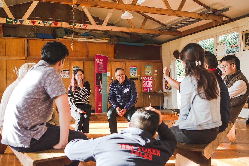 A group of Chinese people sit in a circle in a community hall