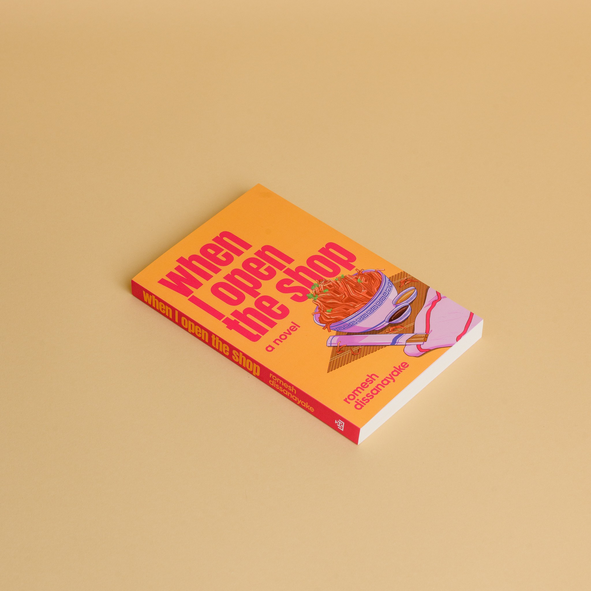 A book with a bowl of noodles on the cover against an orange background